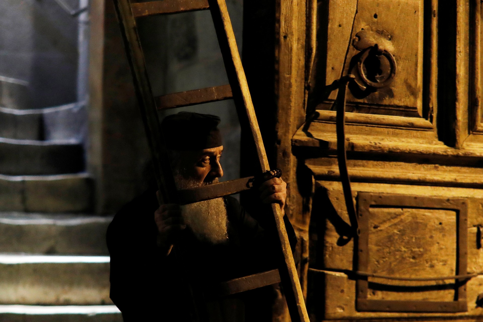 Un sacerdote cristiano ortodoxo sostiene una escalera cerca de la puerta de entrada de la Iglesia del Santo Sepulcro en la Ciudad Vieja de Jerusalén, 17 de noviembre de 2018.