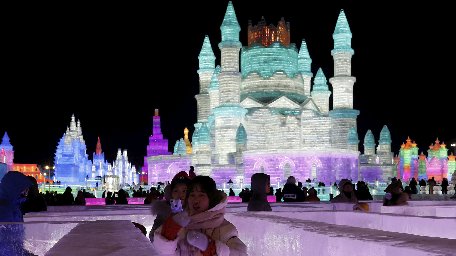 Una madre y su hija podan para una foto en frente de un castillo de hielo en Harbin