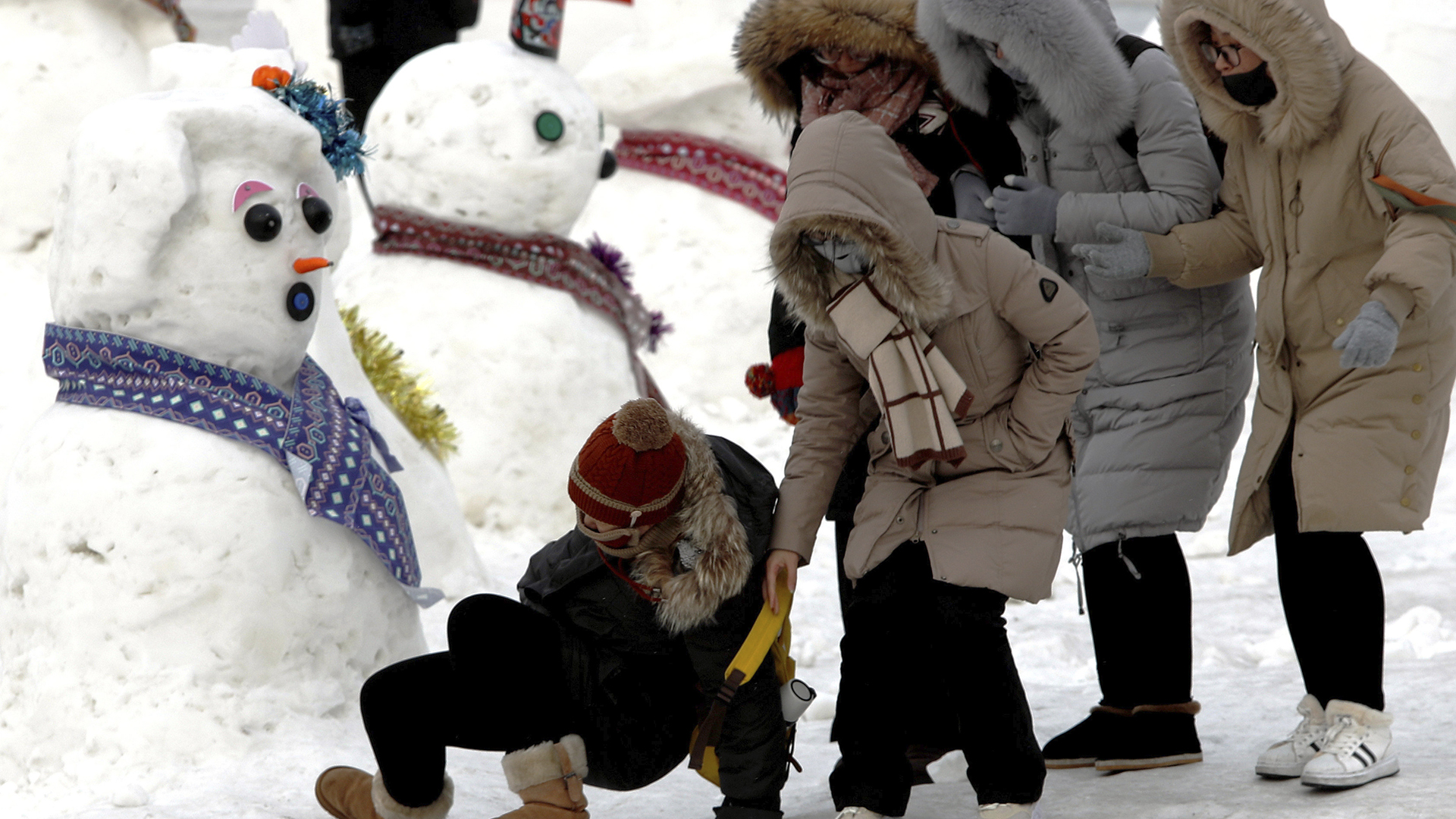 Niños juegan en la nieve con sus trineos en Harbin