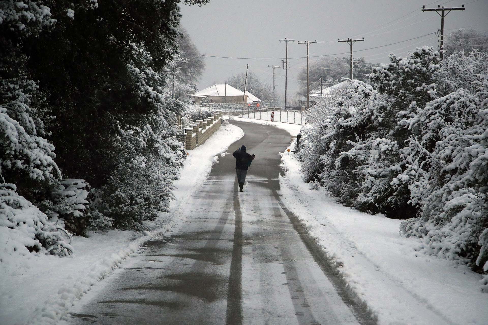 Un residente esparce sal en las calles de Myrodafni, cerca de la ciudad de Ioannina, al norte de Grecia (AP Photo/Thanassis Stavrakis)