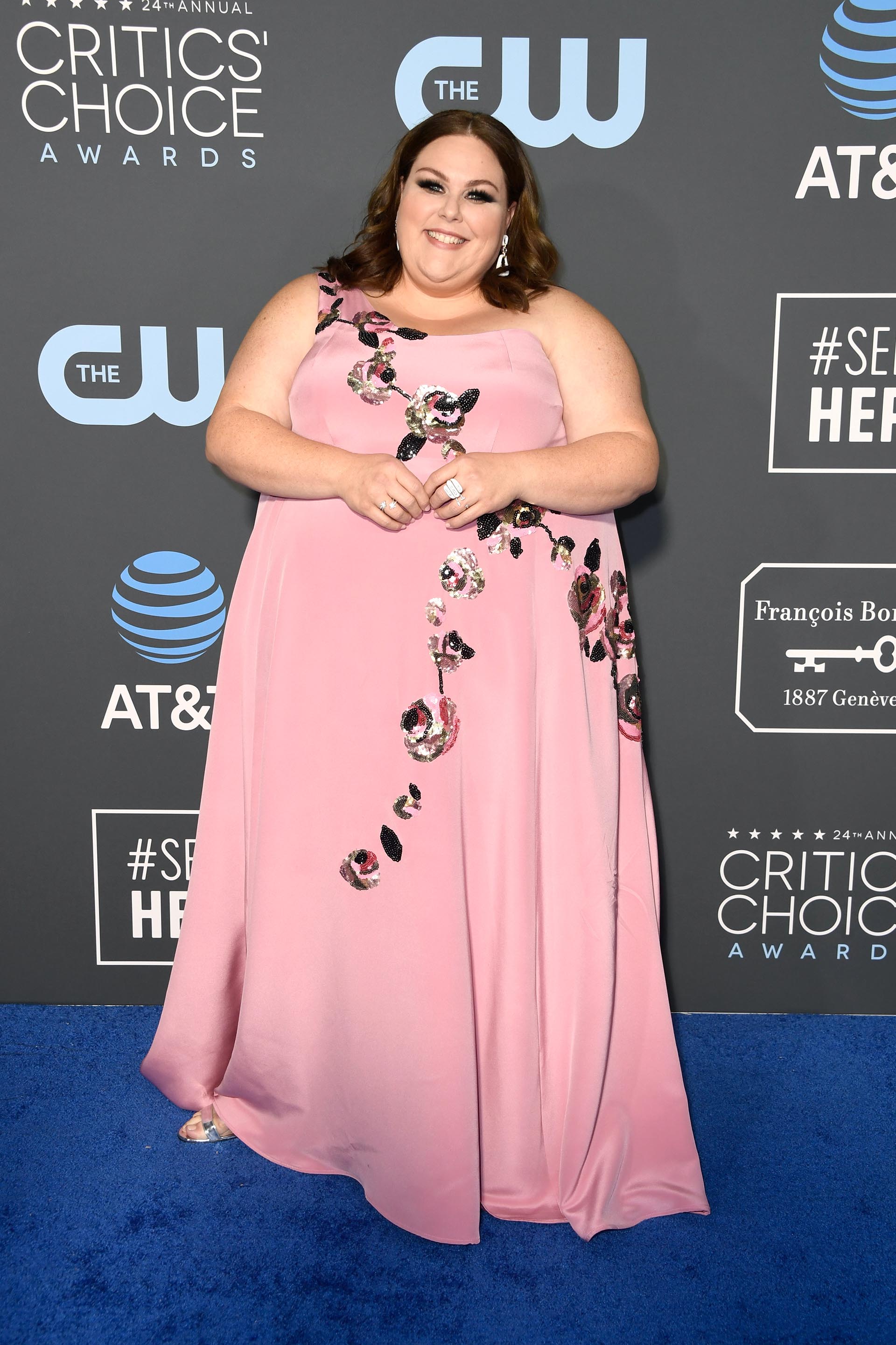 Chrissy Metz, enfundada en un vestido rosado de un solo hombro con bordado de flores. Completó su look con pequeñas joyas: dos anillos y aros gota