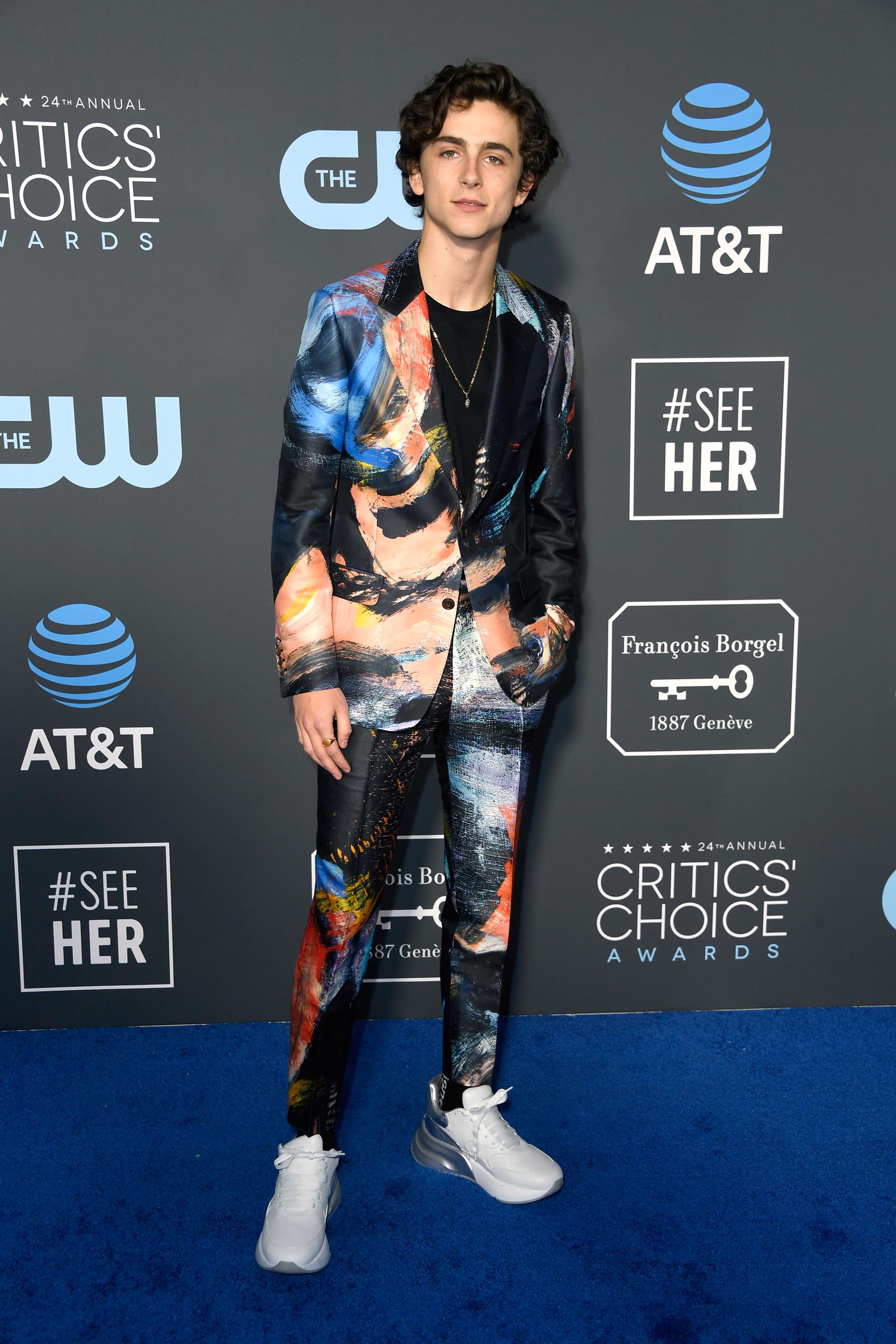 Timothee Chalamet, el millennial pasó por la blue carpet y lució un sporty chic look. Impactó con la elección de su esmoquin. Estampado abstracto pintado y reemplazo de camisa por remera de algodón. El detalle sporty, en sus pies: las zapatillas