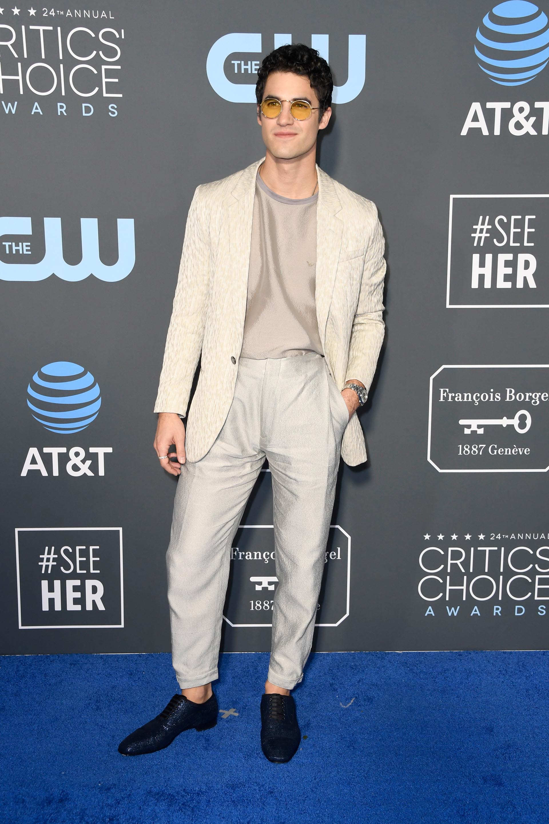 Darren Crissc con un look desestructurado y fuera del dress code elegante, apostó por un pantalón pescador de gabardina, un saco tramado en blanco off white y remera. Para sus pies, zapatos tramados metalizados. El detalle fashion, unos anteojos vintage redondos amarillos