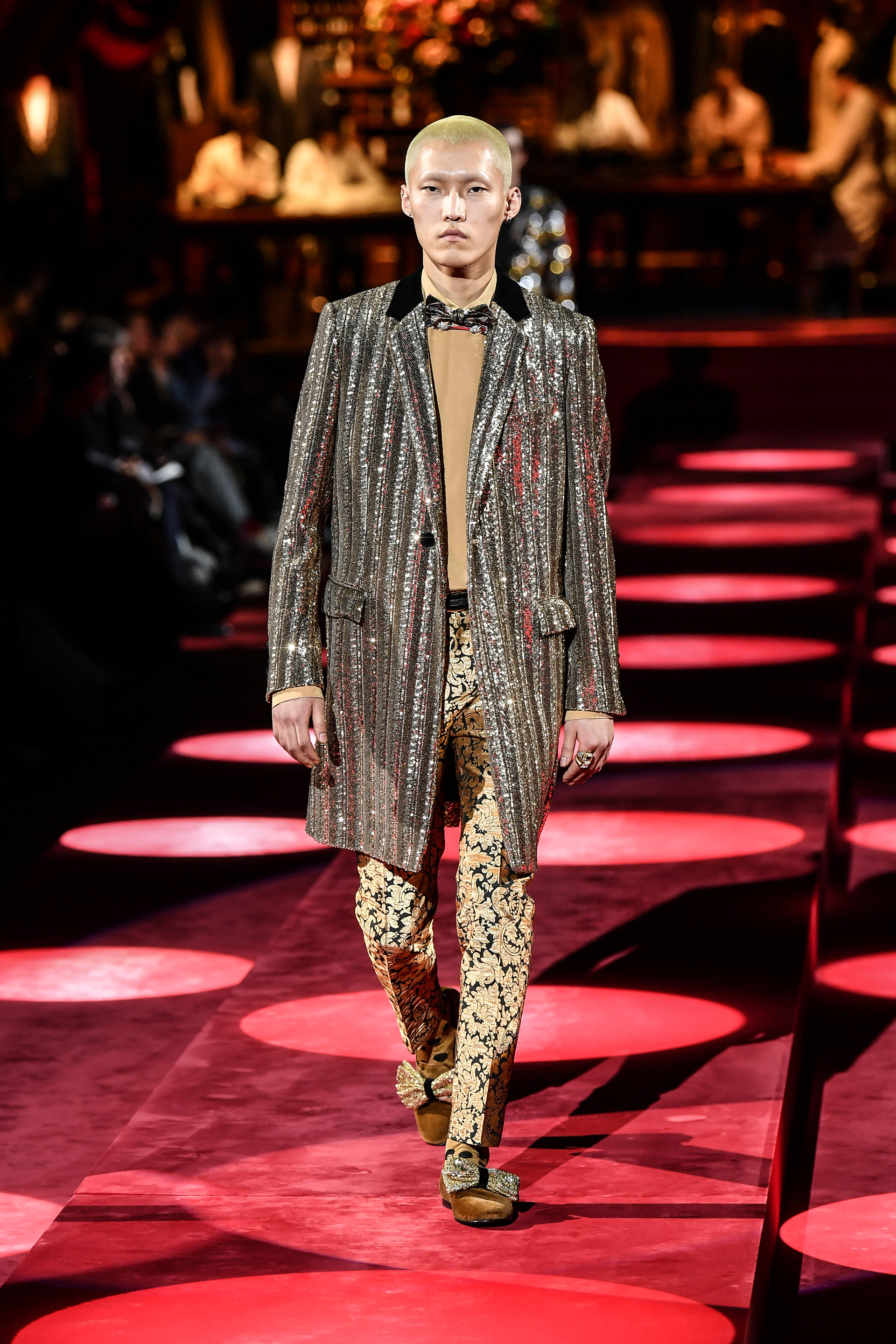 Un sacón con paillettes en dorado fue el gran protagonista del look. Acompañado por un pantalón pinzado estampado de búlgaros y una polera de modal con un moño