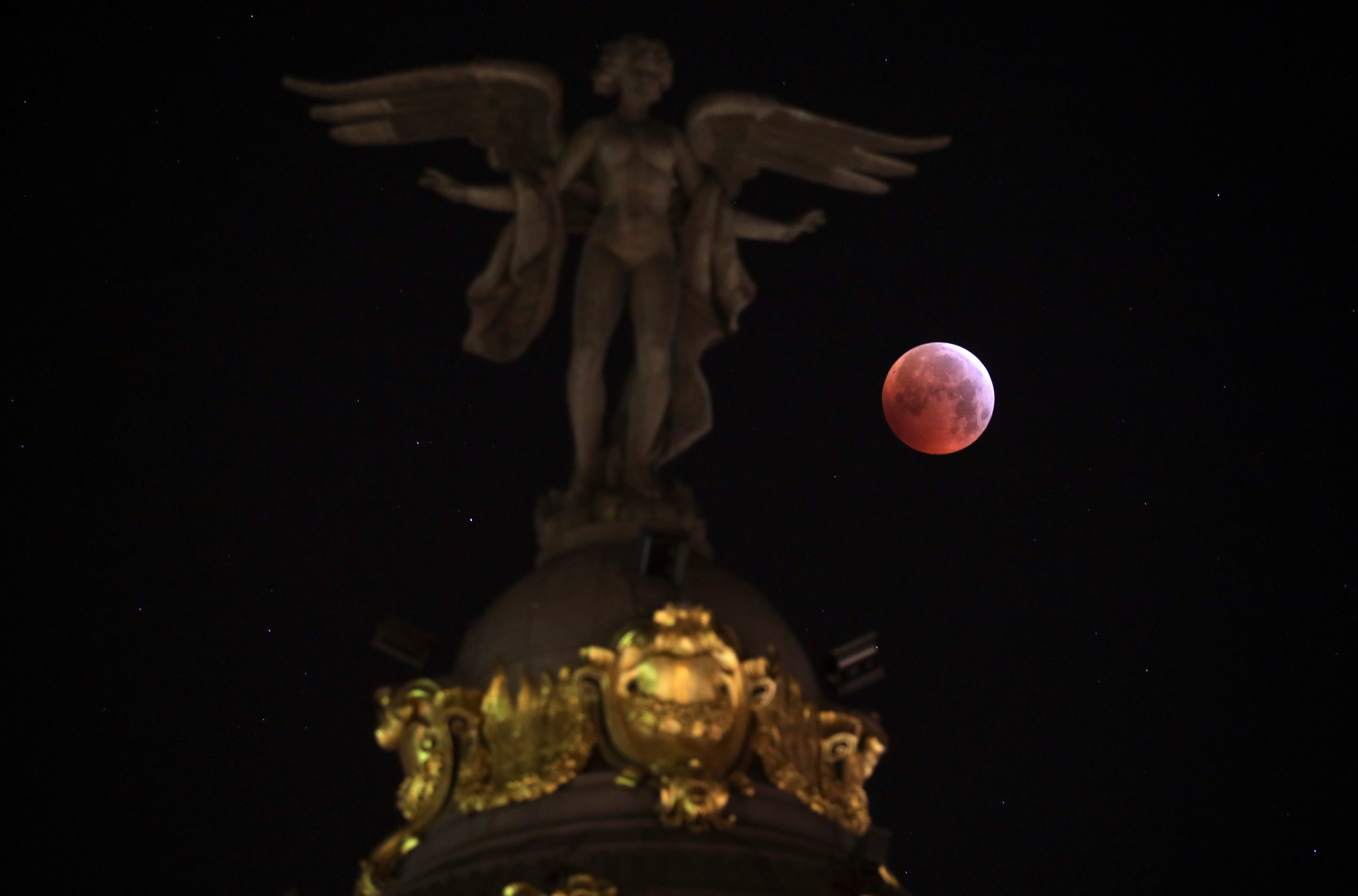 La luna detrás de la estatua de la “Victoria Alada” del edificio Metropoli en Madrid (REUTERS/Sergio Perez)