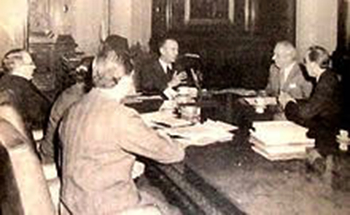 Luis Cerruti Costa (al fondo) de saco negro y anteojos, el presidente de facto Lonardi (en la cabecera de la mesa), Luis Natalini, secretario general del gremio de Luz y Fuerza, y a Andrés Framini, titular de la Asociación Obrera Textil