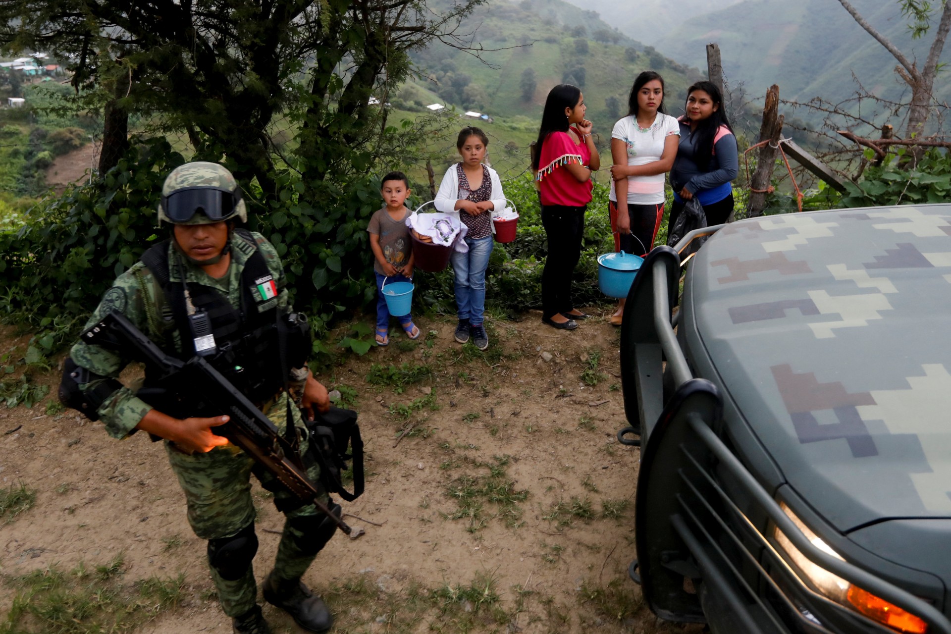 Un soldado se para cerca de los residentes cuando llega al área donde encontraron una plantación ilegal de opio en la Sierra Madre del Sur, en el estado sureño de Guerrero, México, el 24 de agosto de 2018.