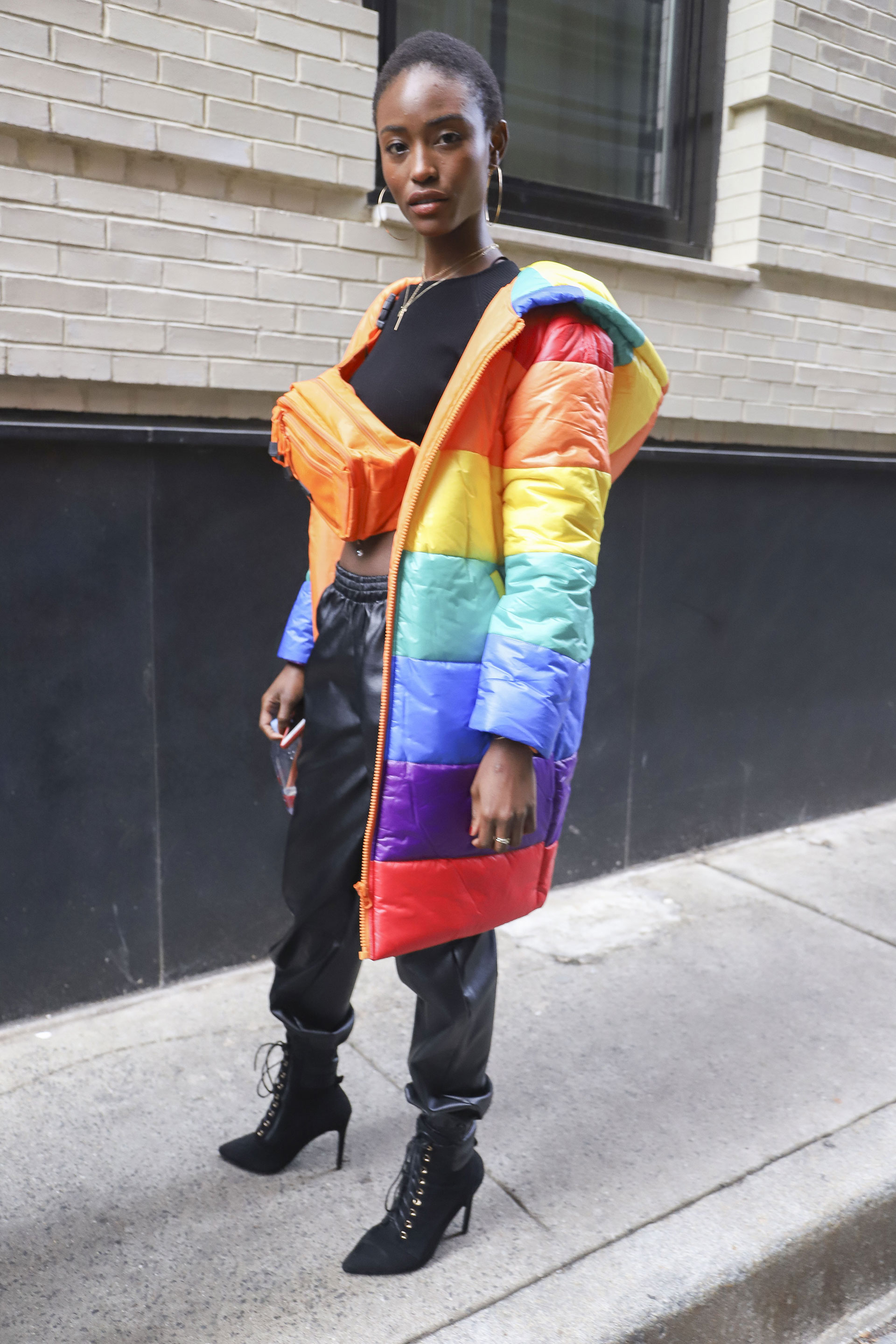 Las puffer jackets siguen vigentes. Multicolor, XL, con capucha y a la rodilla, el diseño que se luce por las calles de NY. Un conjunto de crop top negro y pantalón de cuero abullonado con booties acordonadas. ¿El detalle fashionista? La riñonera en naranja flúor