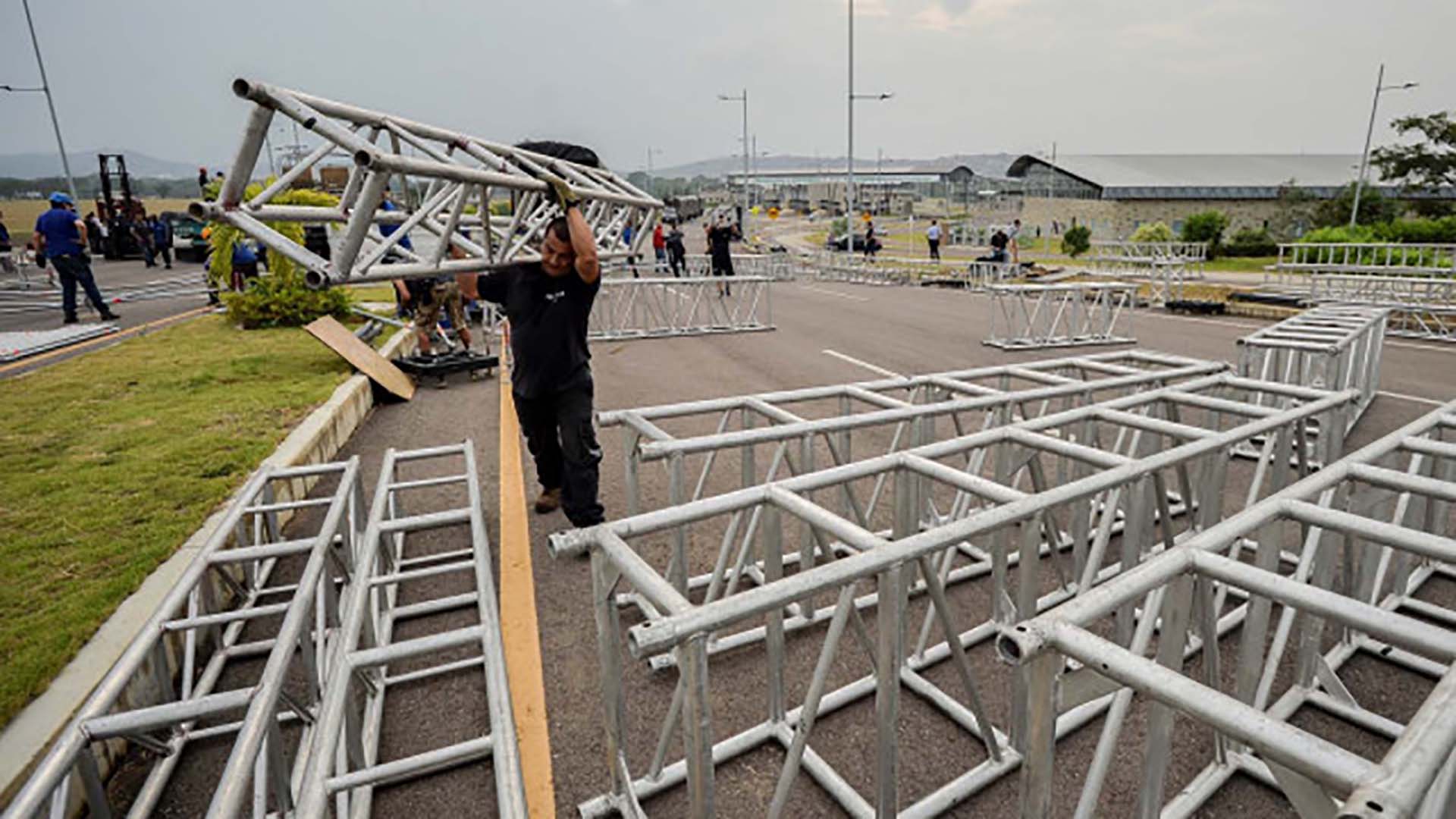 Decenas de trabajadores montan el escenario para el viernes 22 de febrero (Photo by Luis ROBAYO / AFP)