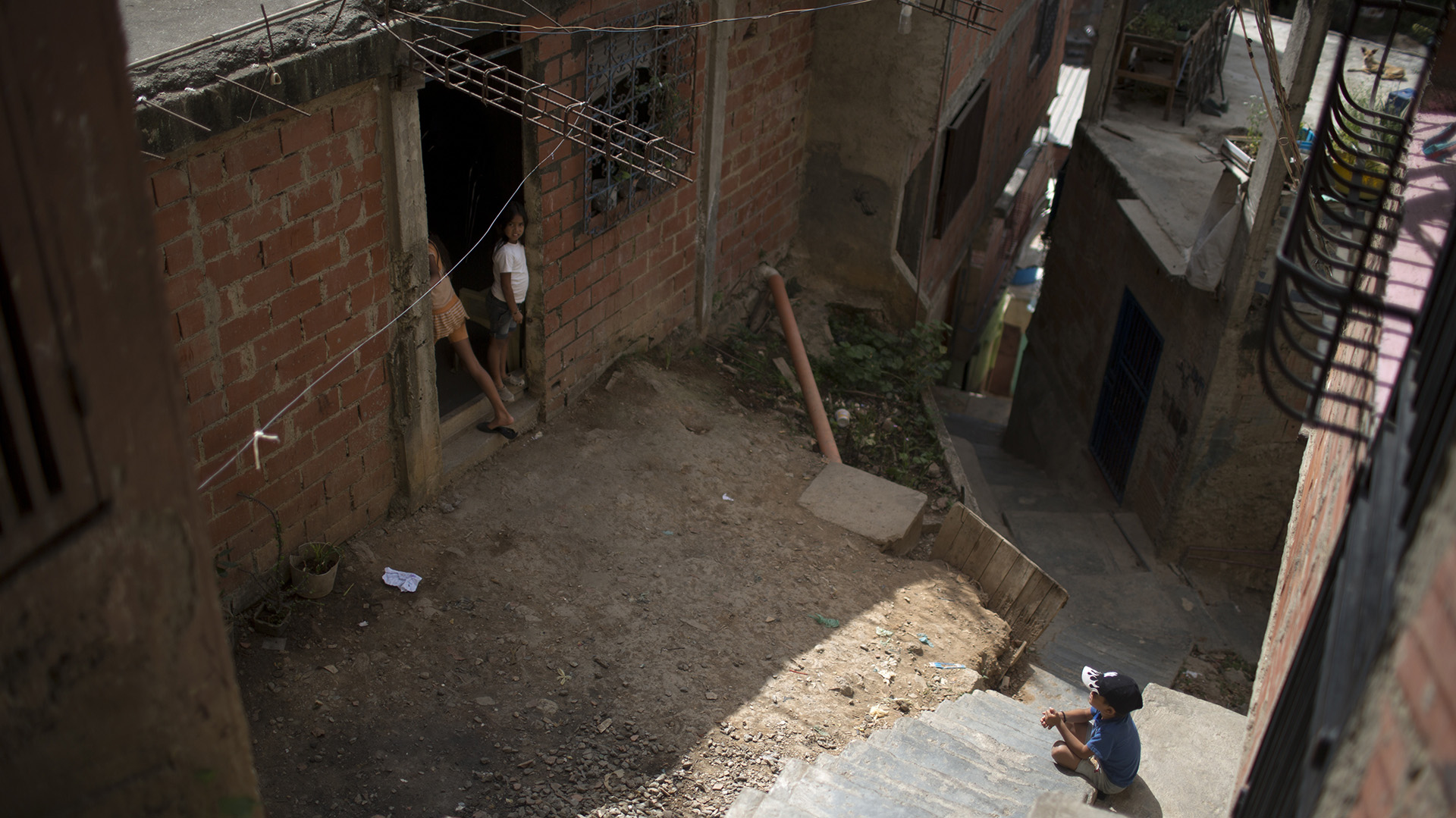Niños se reúnen en la entrada de la que era la casa de Jhonny Godoy en La Vega, Caracas (AP/Ariana Cubillos)