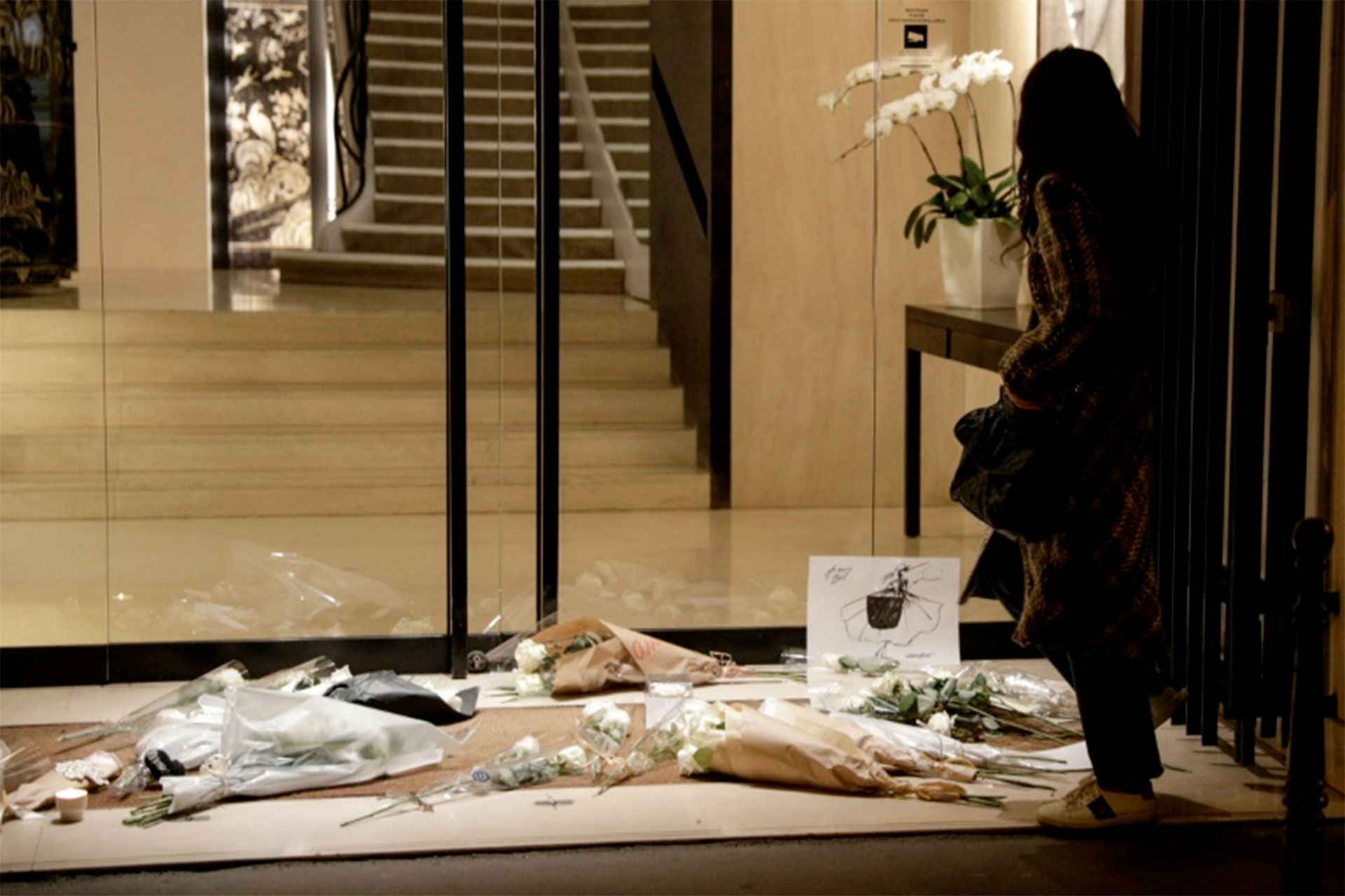 Una mujer permanece junto a un homenaje de flores al fallecido diseñador Karl Lagerfeld junto a la casa Chanel, en París, el 19 de febrero de 2019 (AFP – Geoffroy Van Der Hasselt)