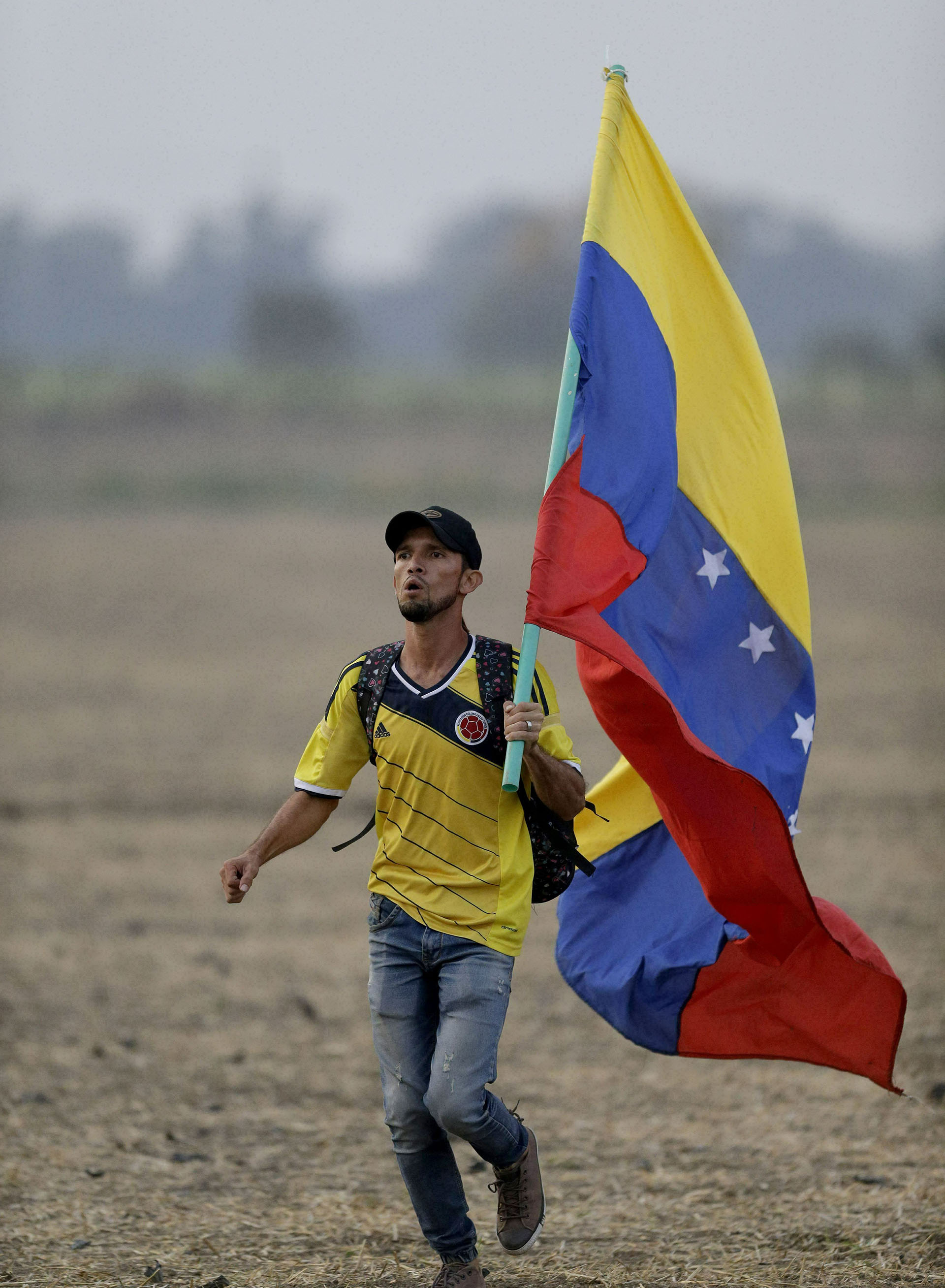 Un hombre con una bandera venezolana corre al llegar al concierto de Venezuela Aid Live. (AP)