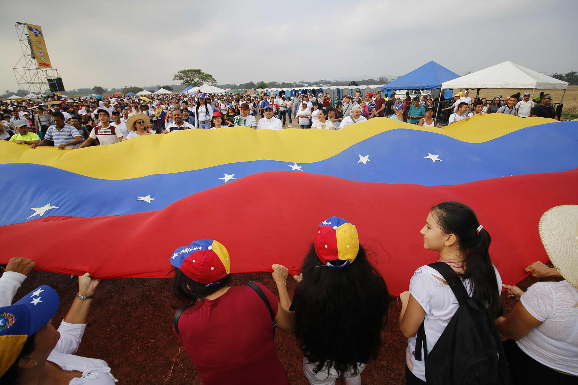 Decenas de venezolanos sostienen una gran bandera de su país en el concierto “Venezuela Aid Live”. (AFP)