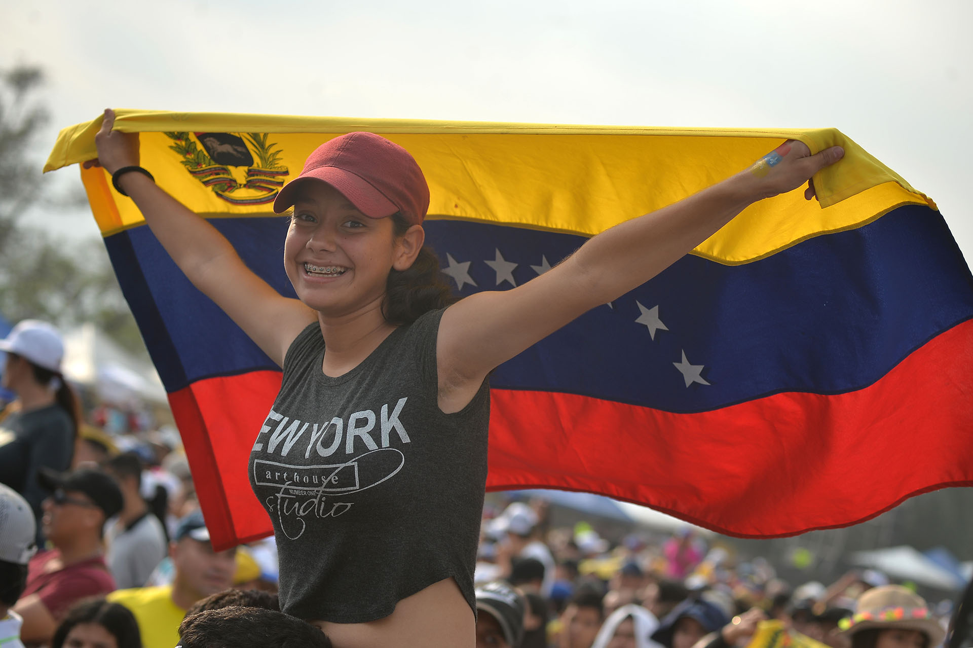Una mujer sostiene una bandera de Venezuela sobre los hombros de un compañero en el concierto “Venezuela Aid Live”. (AFP)