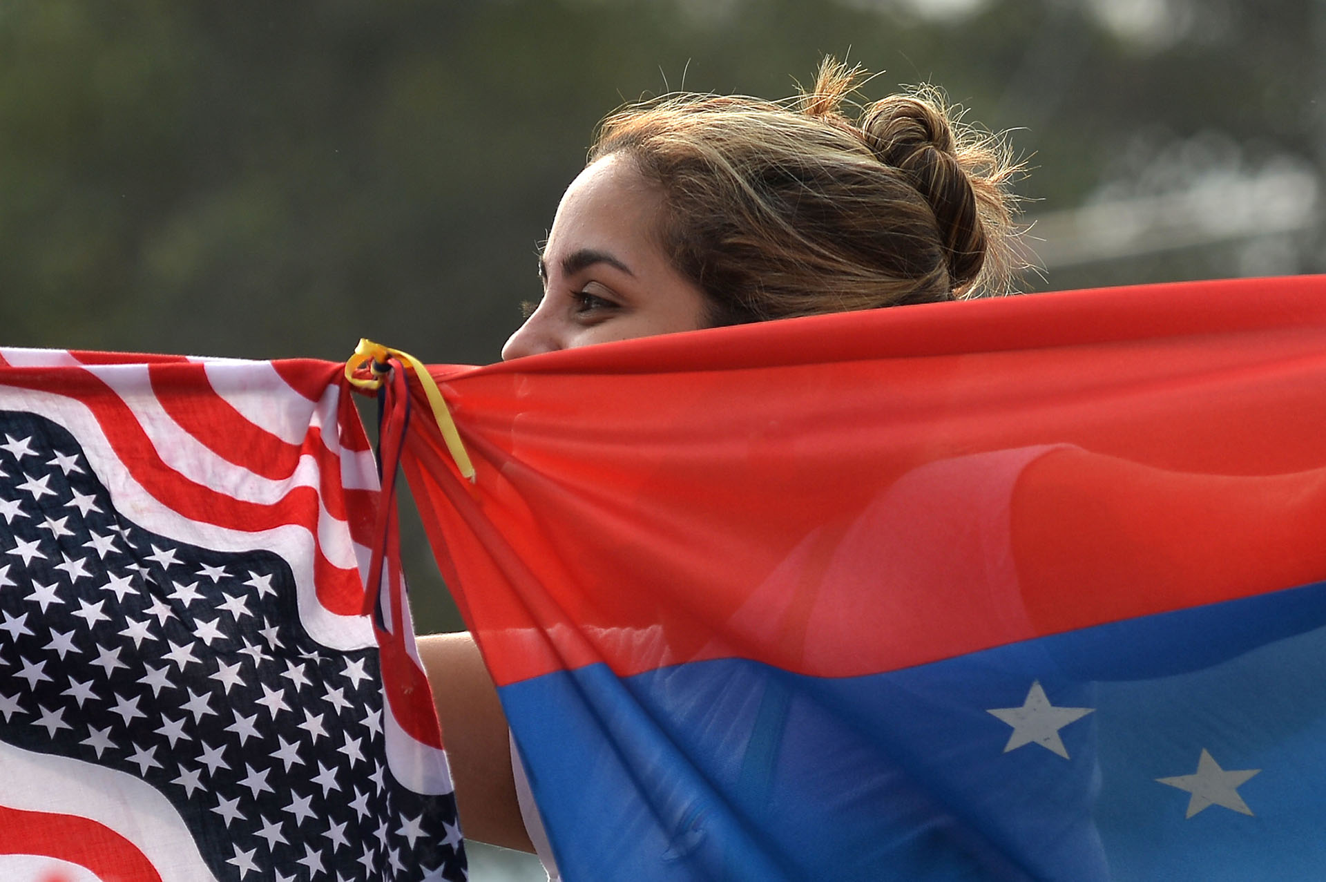 Una mujer junta las banderas de Venezuela y los Estados Unidos.