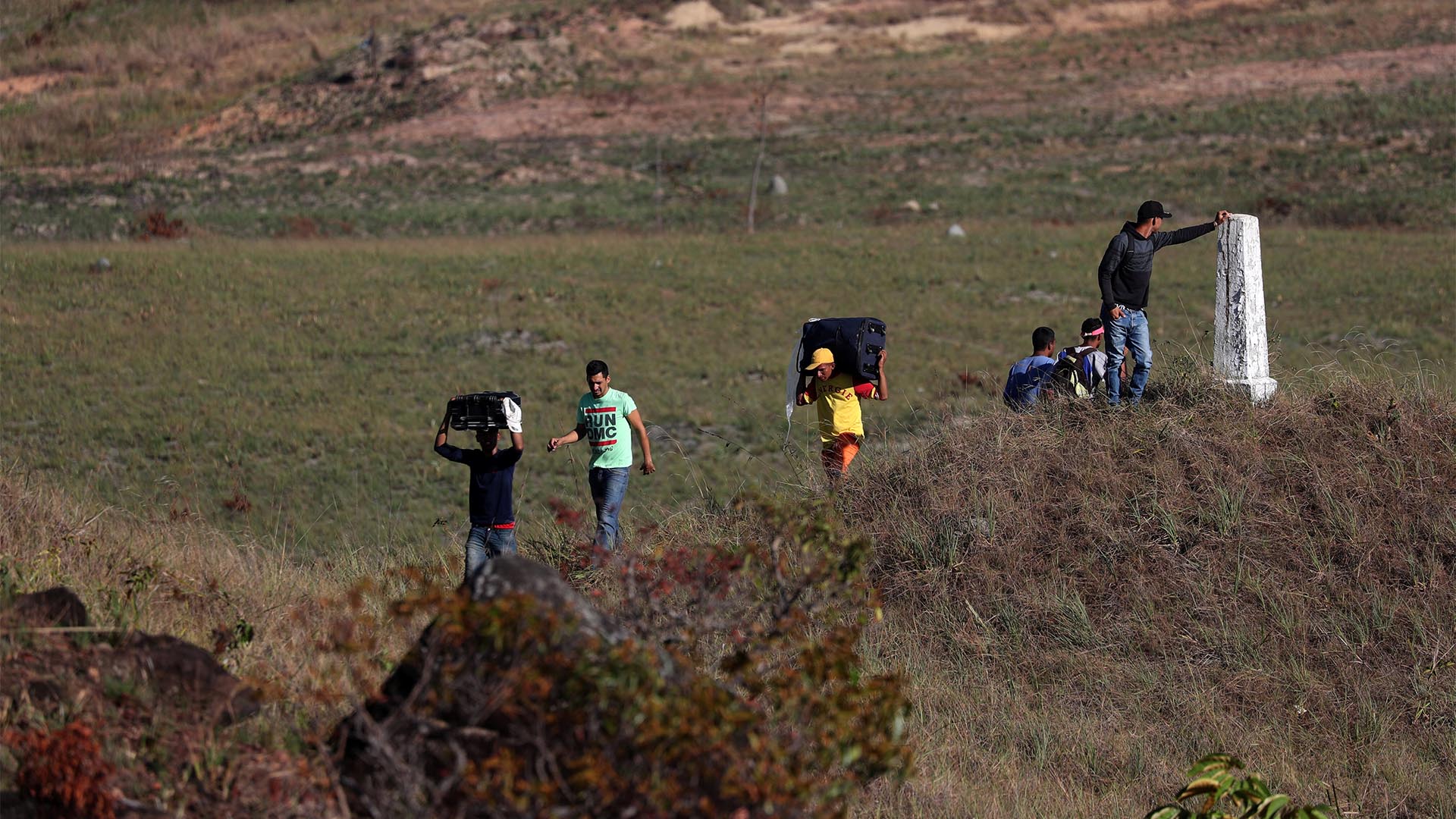 Venezolanos cruzan la frontera entre su país y Colombia desde otro punto de la ciudad de Ureña, con cajas de comida y medicamentos (Reuters)