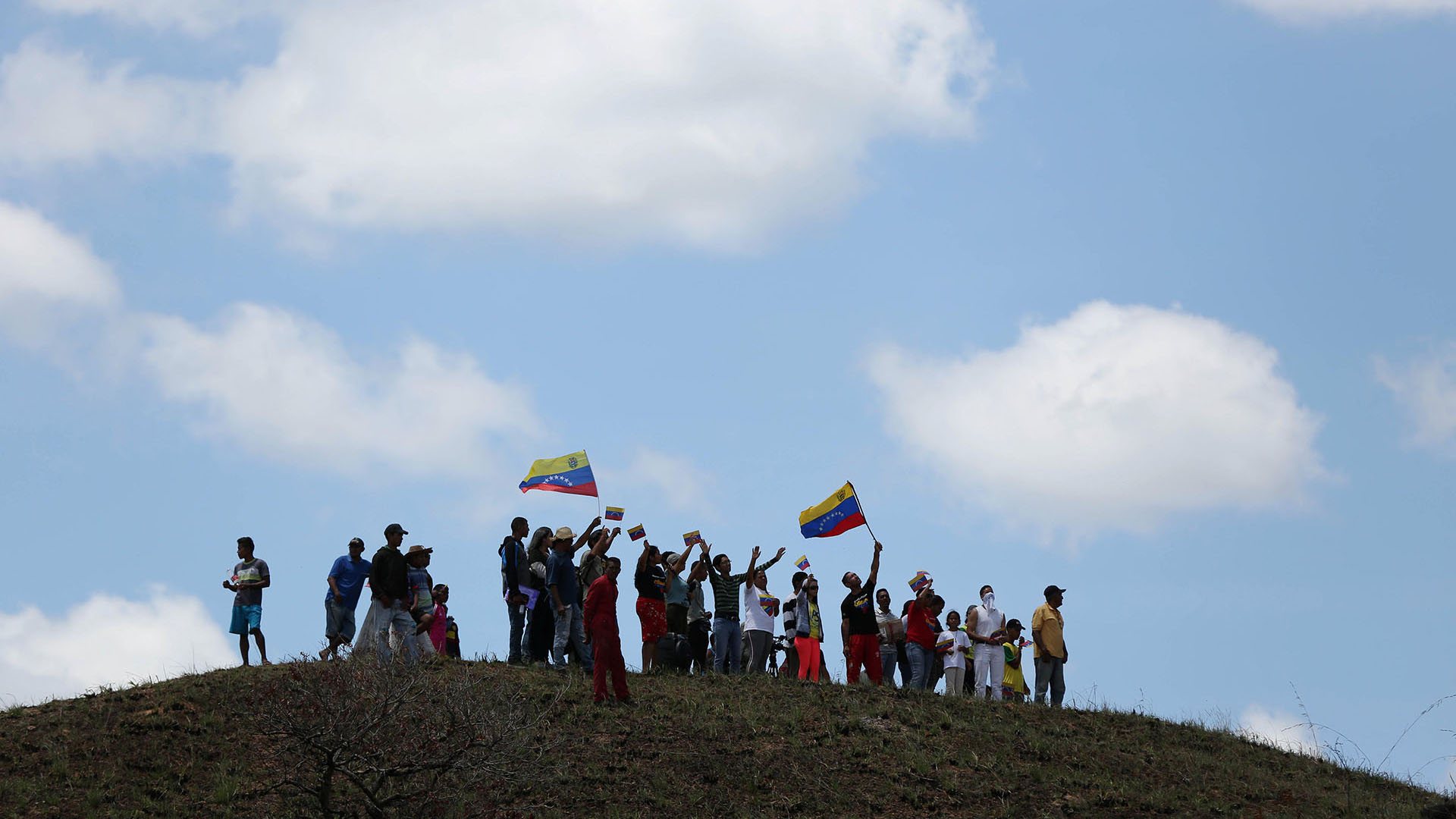 La gente saluda a un camión que lleva ayuda humanitaria mientras cruza a Venezuela desde Brasil (Reuters)