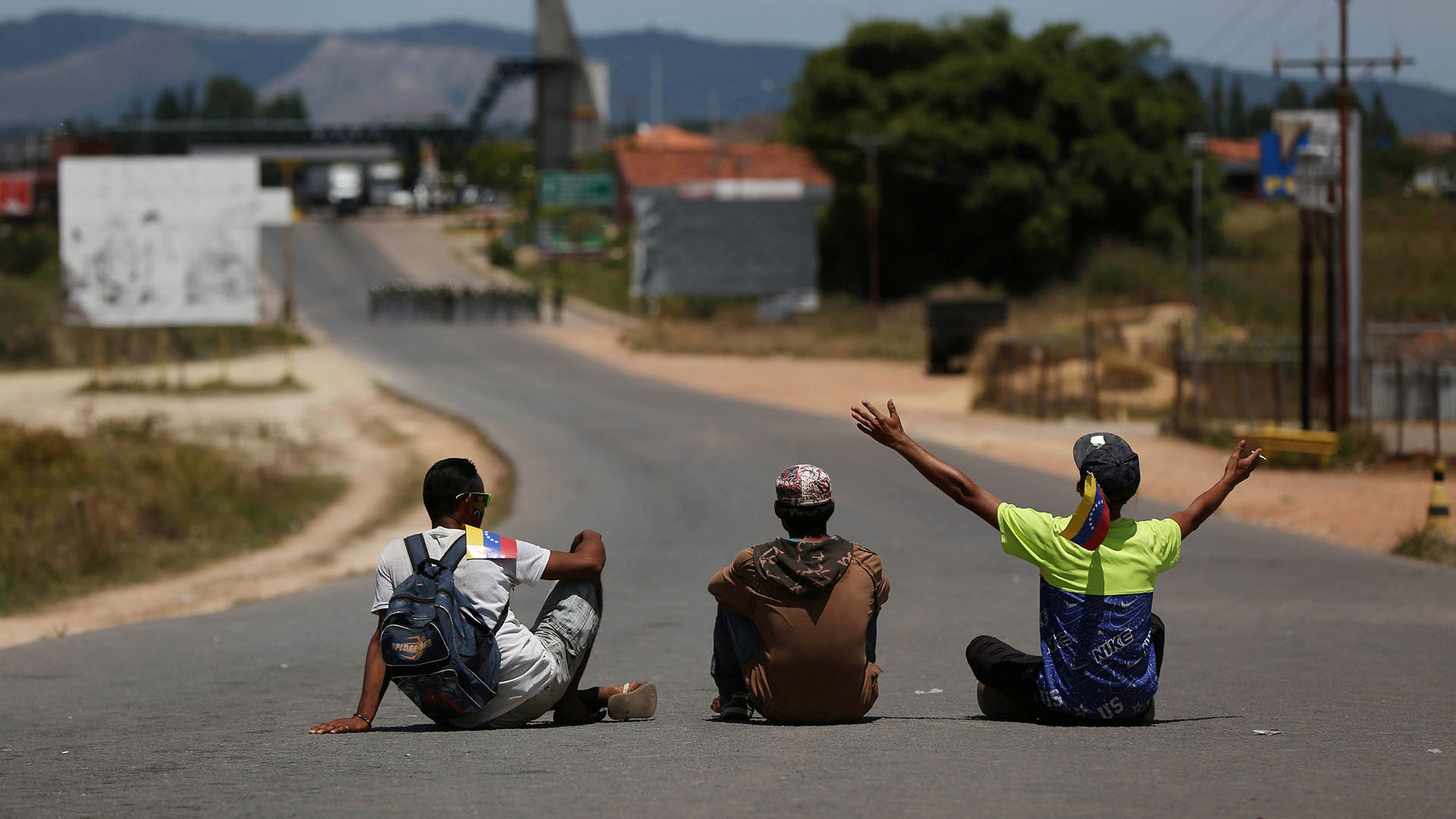 Hombres sentados en el camino de un camión que lleva ayuda humanitaria a Venezuela desde Brasil (Reuters)