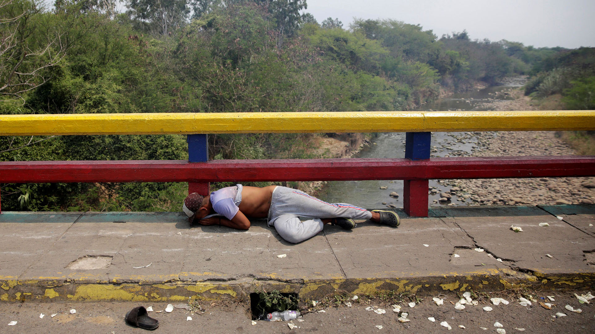 Un manifestante se encuentra en el suelo mientras se enfrenta a las fuerzas de seguridad de Venezuela en el puente Francisco de Paula Santander en la frontera entre Colombia y Venezuela, visto desde Cucuta (Reuters)