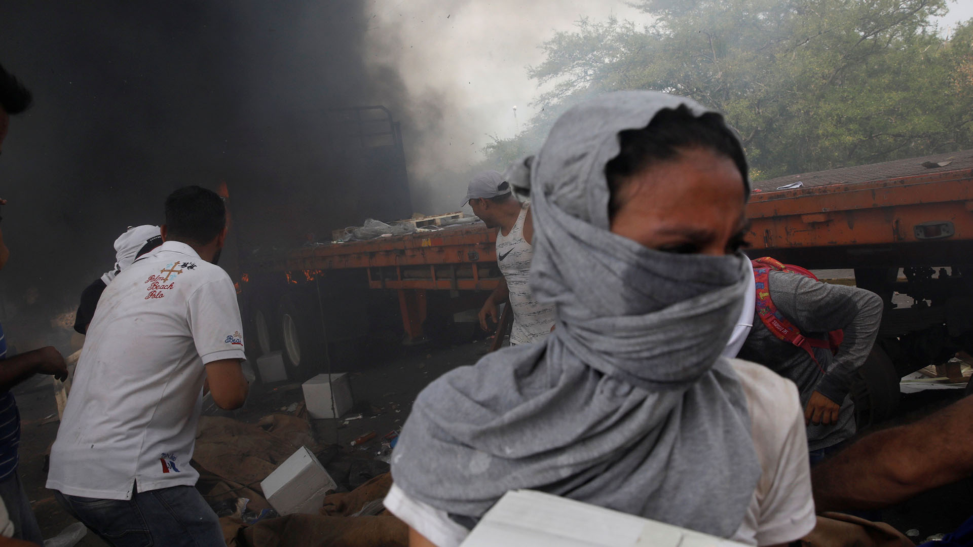 Partidarios de la oposición descargan ayuda humanitaria de un camión que fue incendiado luego de enfrentamientos entre simpatizantes de la oposición y las fuerzas de seguridad de Venezuela en el puente Francisco de Paula Santander en la frontera entre Colombia y Venezuela visto desde Cúcuta (Reuters)