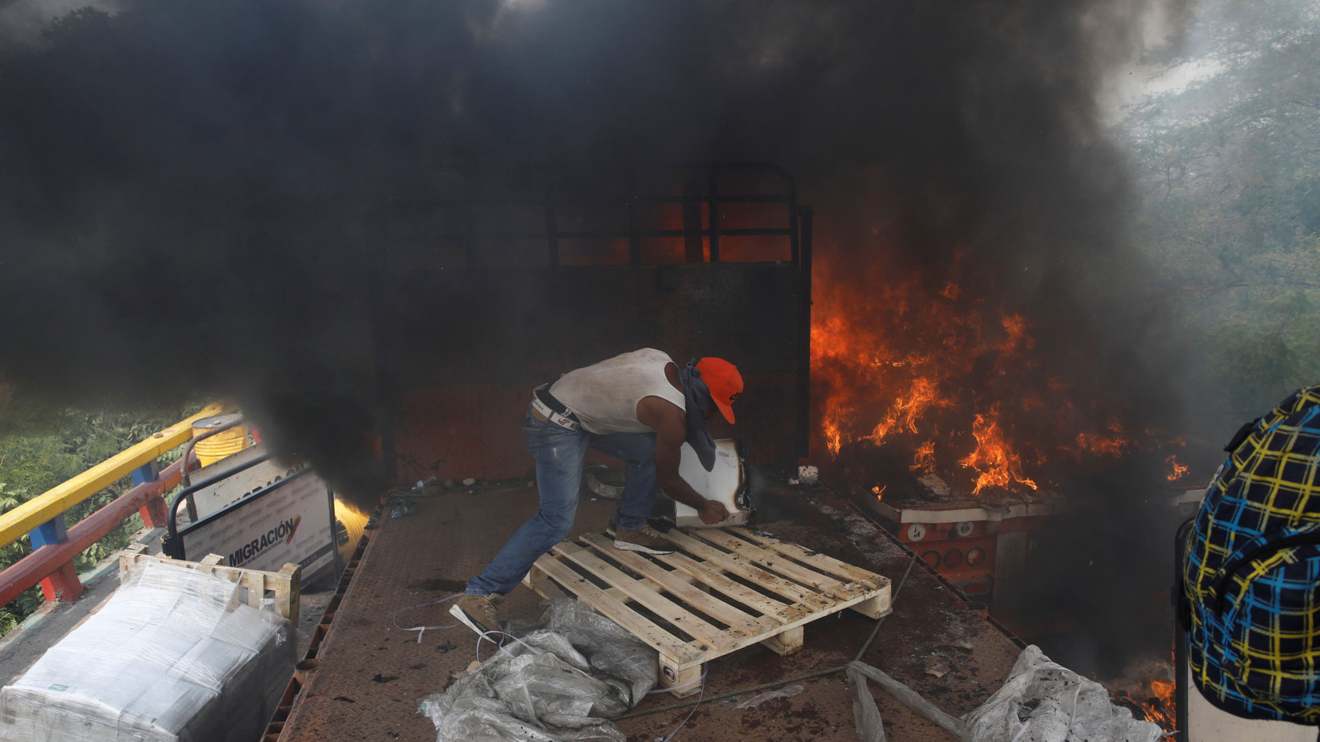 Partidarios de la oposición descargan ayuda humanitaria de un camión que fue incendiado luego de enfrentamientos entre simpatizantes de la oposición y las fuerzas de seguridad de Venezuela en el puente Francisco de Paula Santander en la frontera entre Colombia y Venezuela visto desde Cúcuta (Reuters)