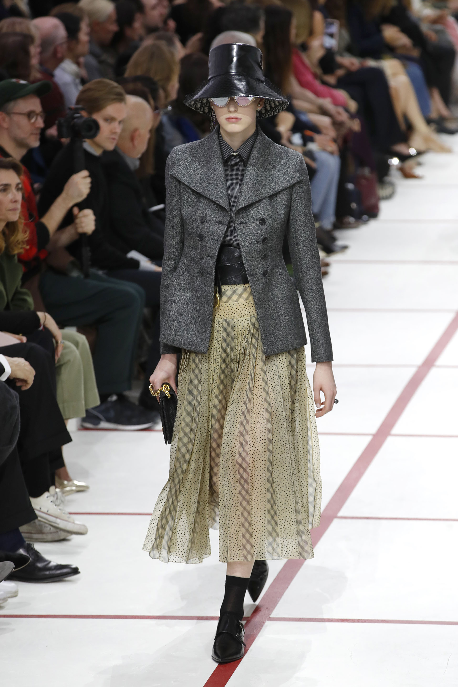 British style y polka dots. Saco de paño en gris oscuro, con camisa y falda cuadrillé y a lunares. En sus pies, booties y medias de nylon. Para la cabeza, el infaltable gorro acharolado con encaje en el interior
