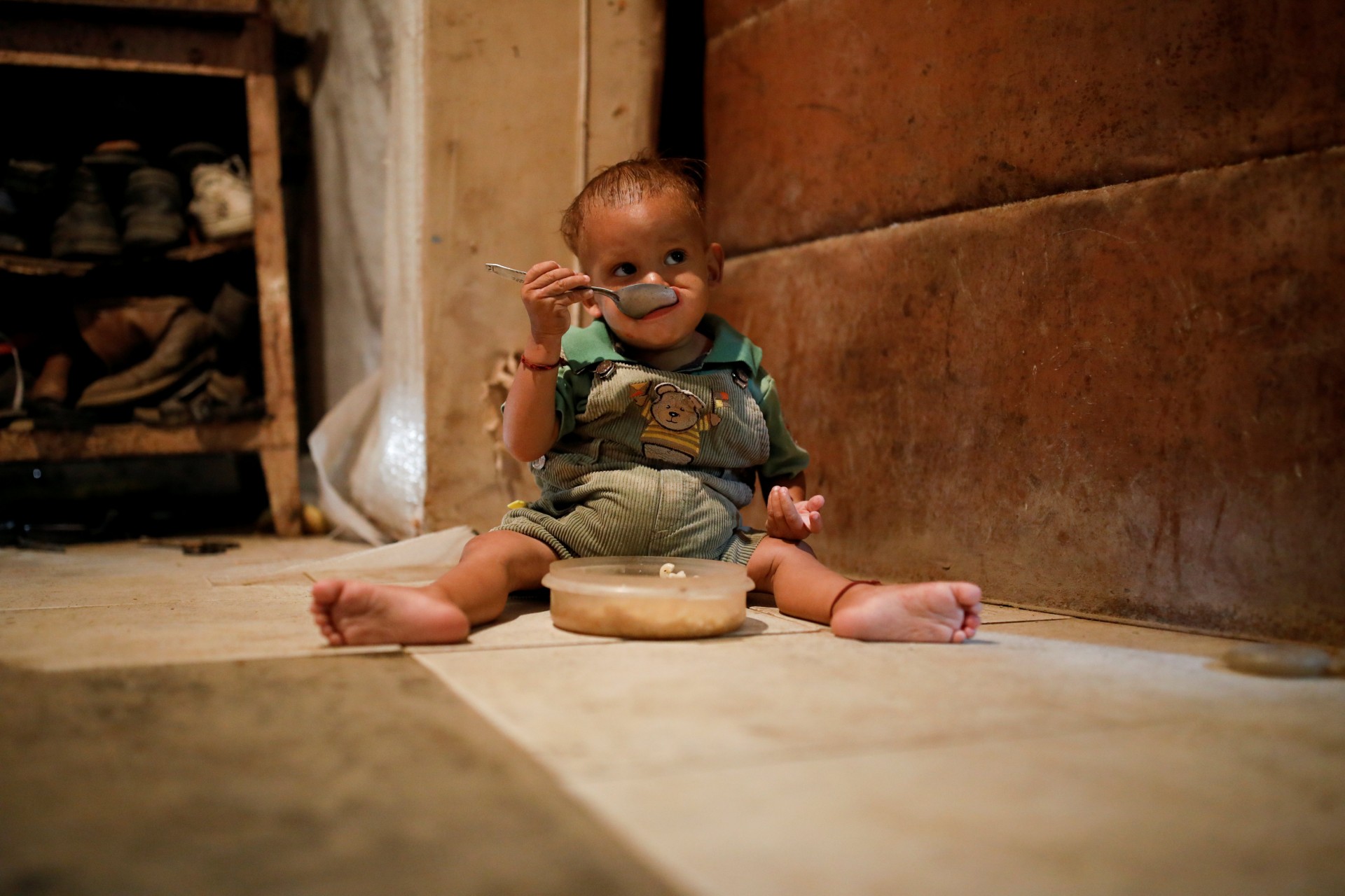 Yeibe Medina, el hijo de un año de María Guitia, se sienta en el suelo alimentándose en su casa cerca de San Francisco de Yare, Venezuela, el 18 de febrero de 2019.