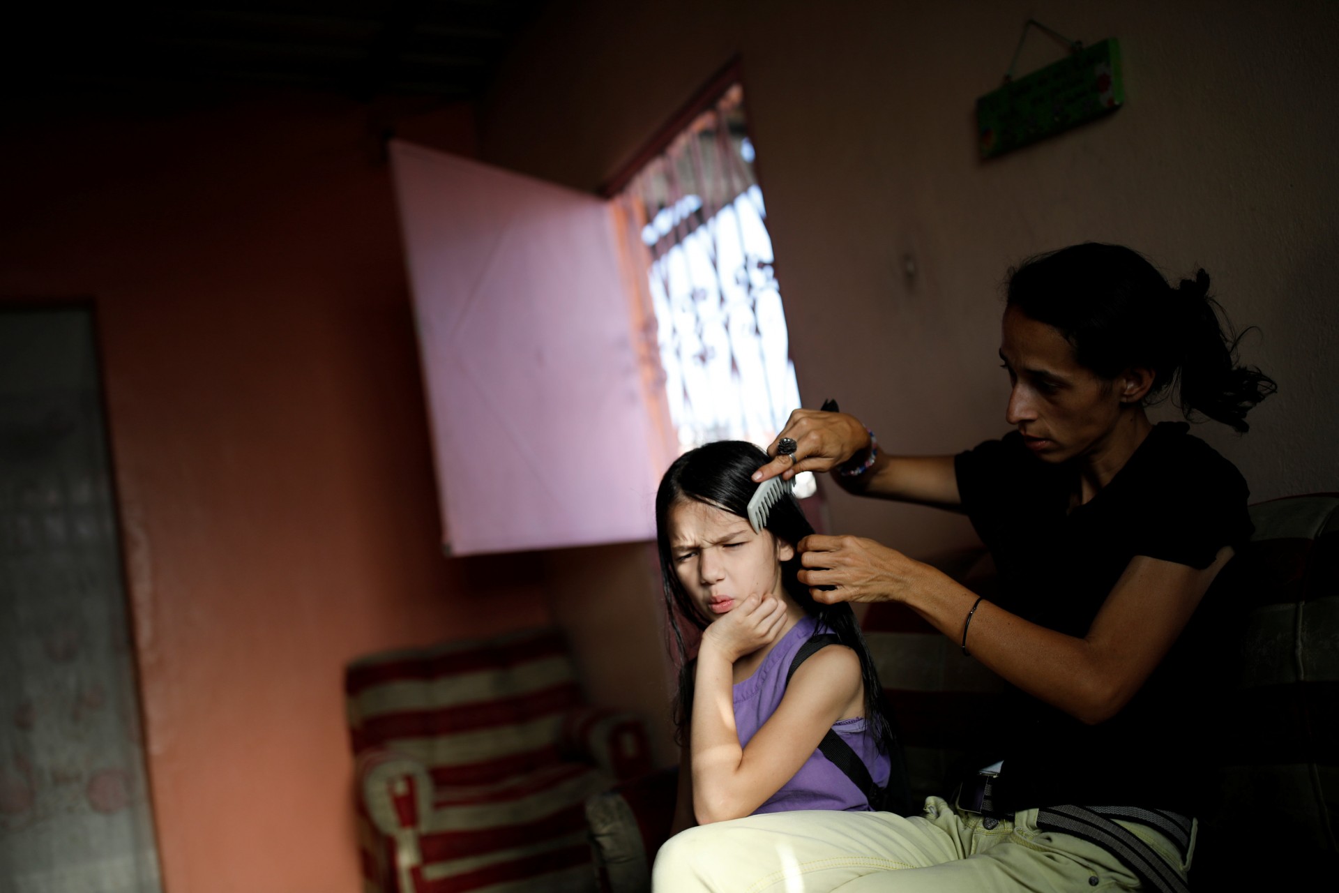 Yaneidi Guzmán, de 38 años, peina el cabello de su hija, en su casa en Caracas, Venezuela, el 19 de marzo de 2018.