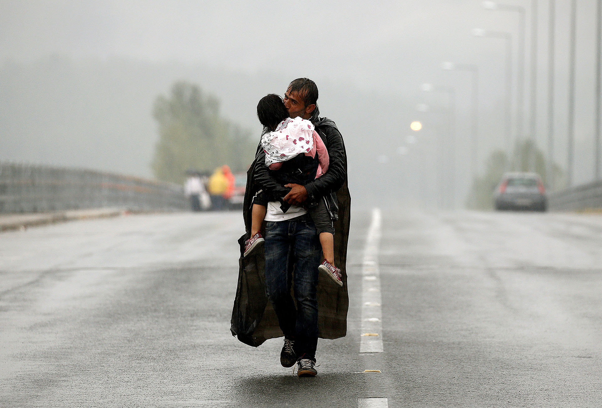Un refugiado sirio besa a su hija mientras camina bajo la lluvia hacia la frontera entre Grecia y Macedonia, en septiembre de 2015