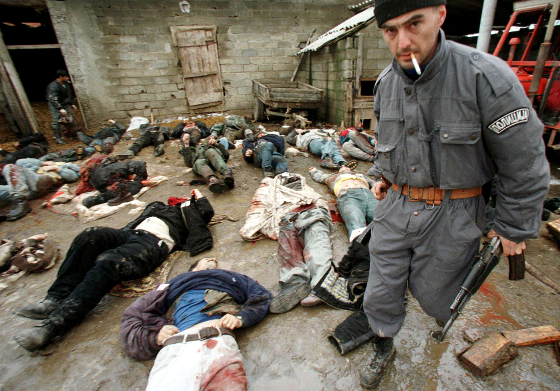 Un policía serbio recoge un rifle AK-47 de un guerrillero de Kosovo, en enero de 1999