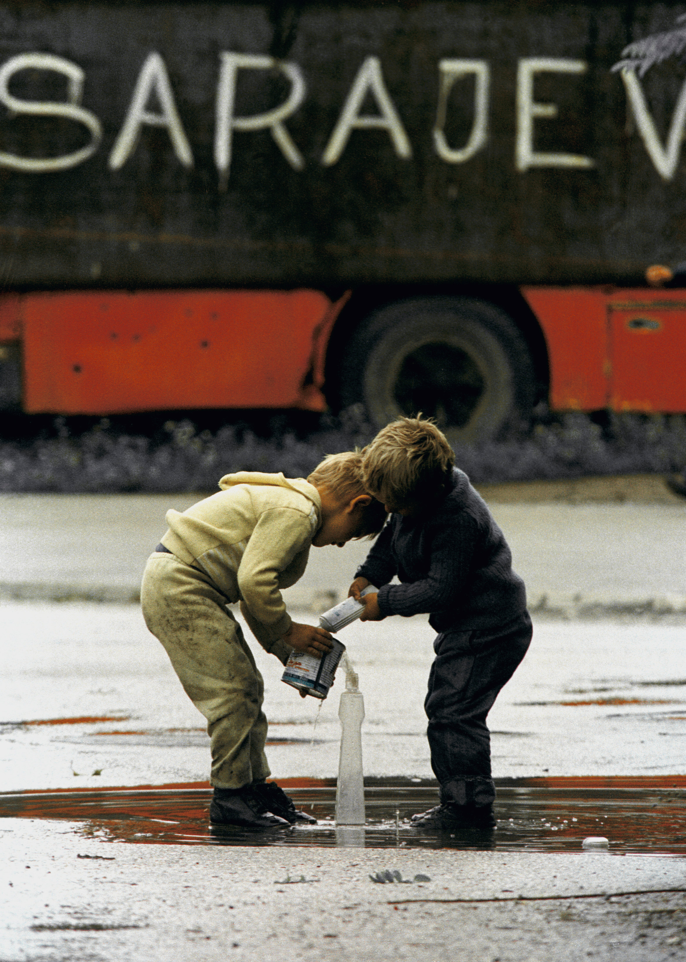 Niños bosnios tratan de juntar agua de lluvia en un charco de Sarajevo, en agosto de 1993