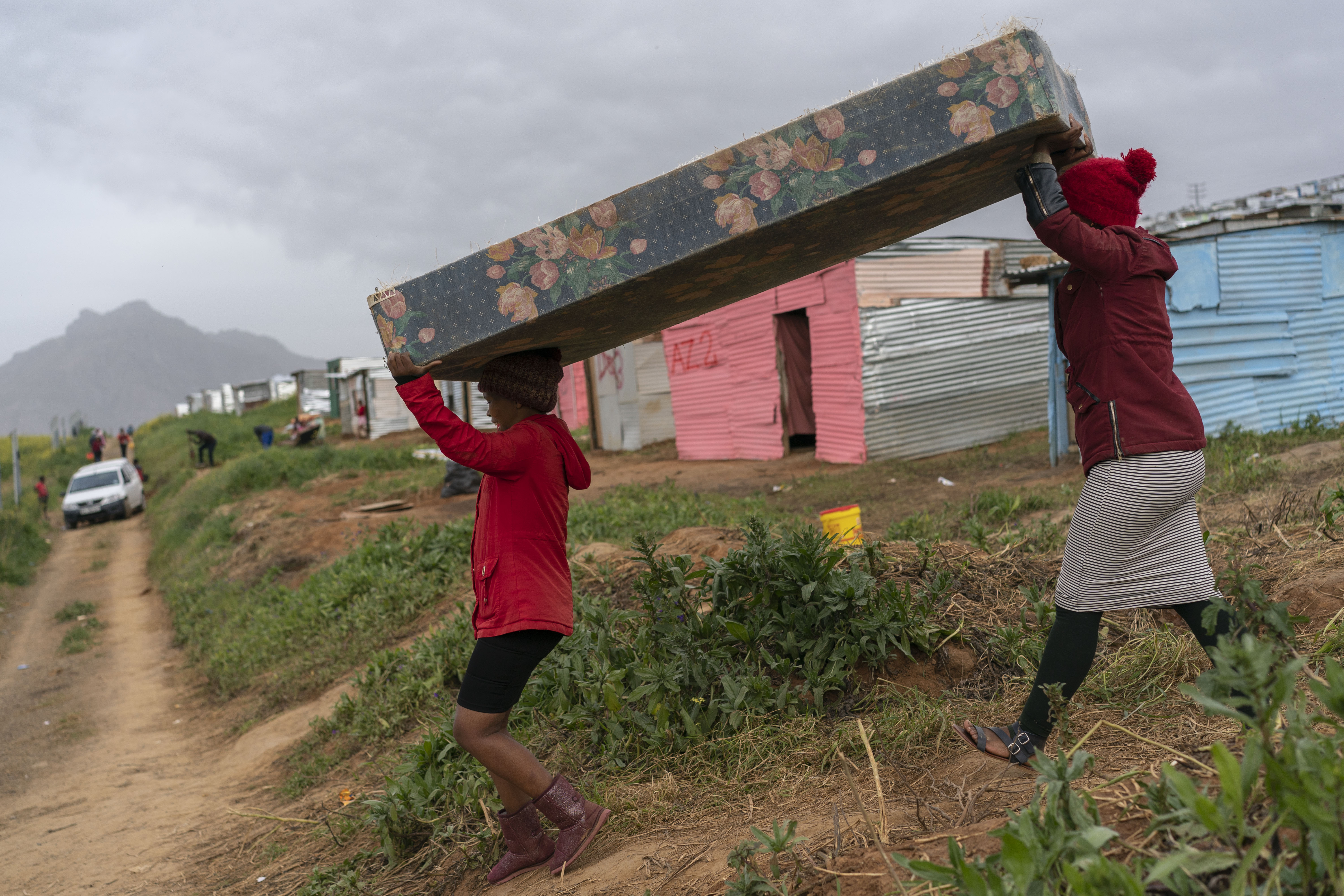 Cargando un colchón a una choza recién construida. (Joao Silva/The New York Times)