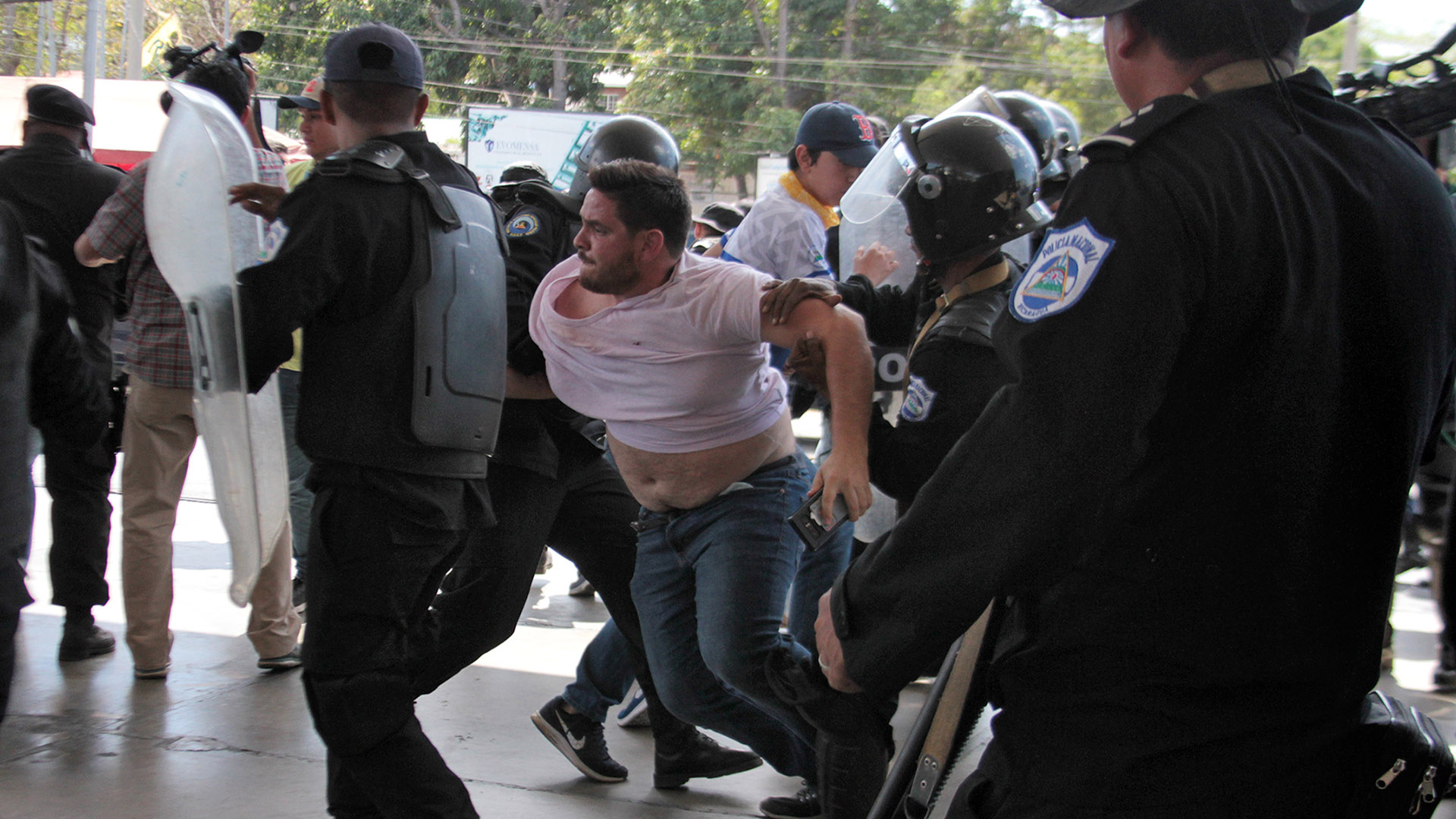 Un agente da policía de Nicaragua forcejea con el fotógrafo de AFP Luis Sequeira en medio de las detenciones de dirigentes opositores este sábado en Managua (Photo by Maynor Valenzuela / AFP)