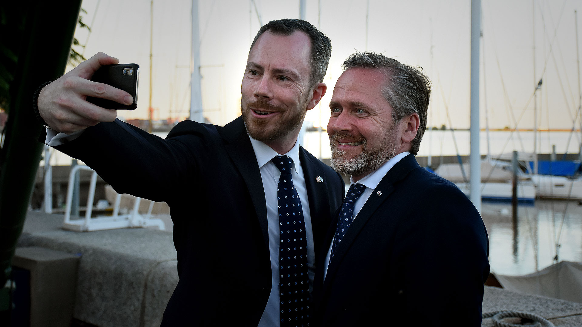 El ministro de Medio Ambiente y Agricultura, Jakob Ellemann-Jensen y Ministro de Relaciones Exteriores, Anders Samuelsen, posan juntos para un selfie con la imagen del atardecer en Puerto Madero