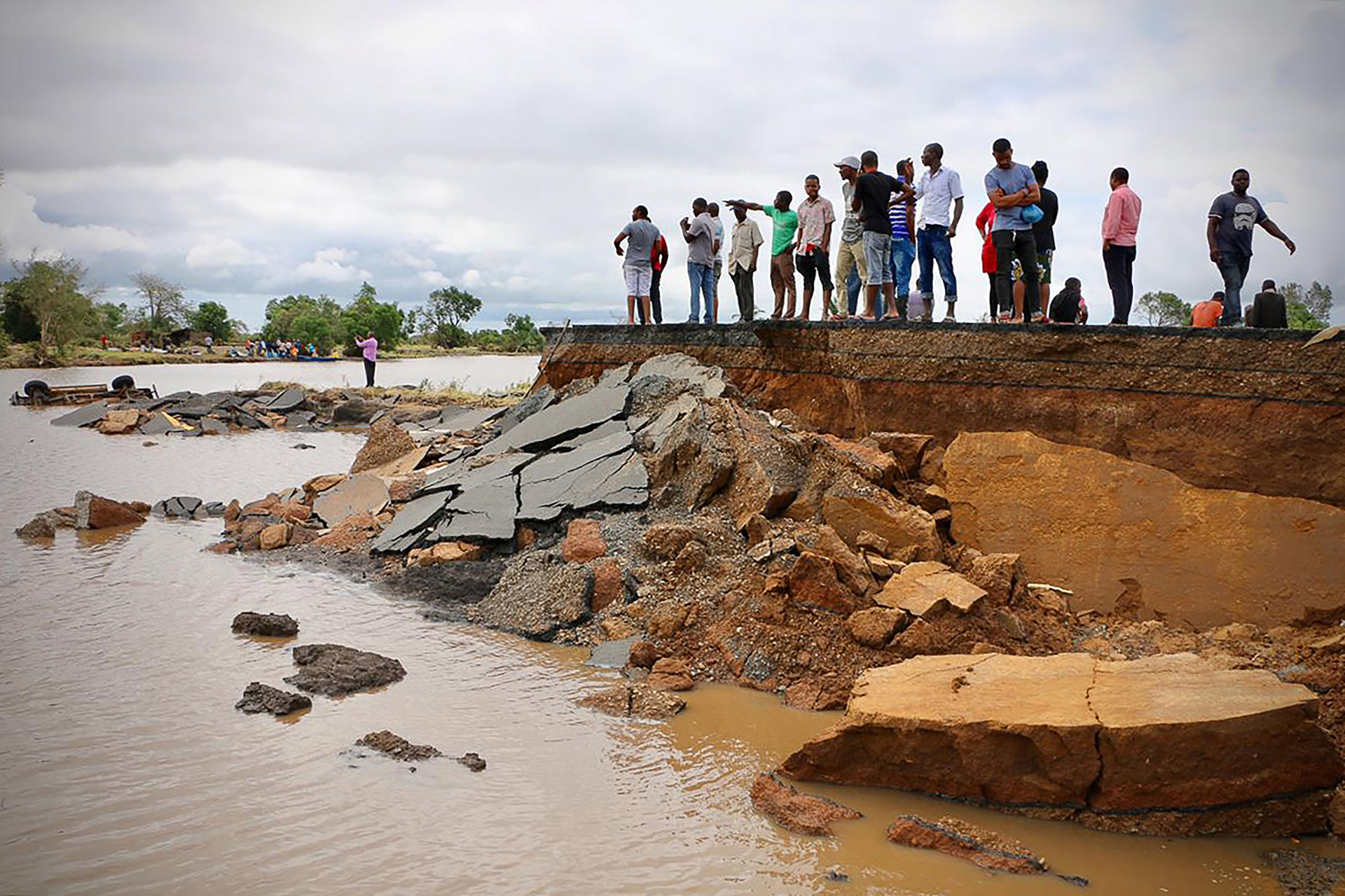 Los locales se ubican junto a una sección dañada de la carretera entre Beira y Chimoio en el distrito de Nhamatanda, en el centro de Mozambique, el 19 de marzo (Photo by ADRIEN BARBIER / AFP)