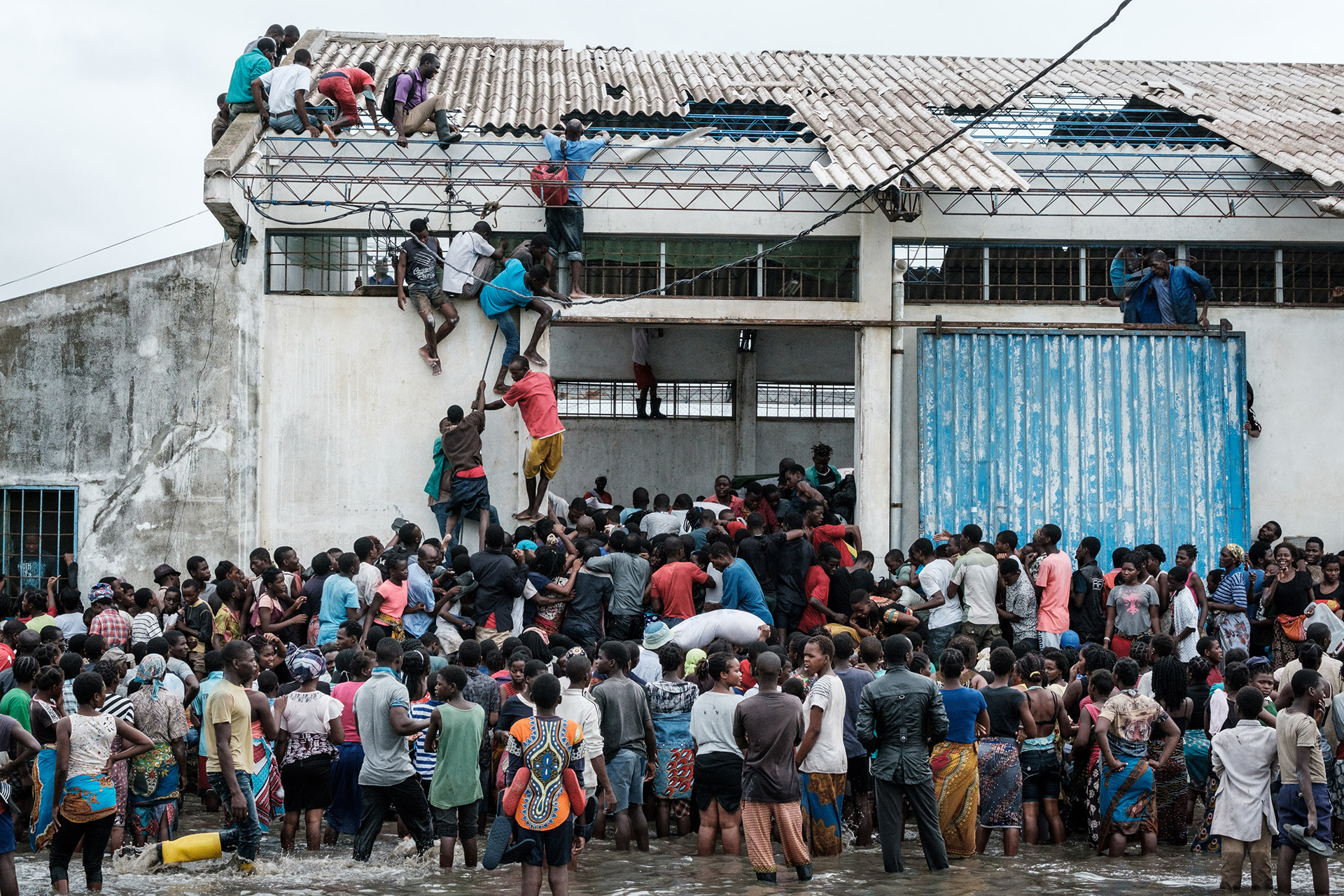 Las personas participan en los saqueos de arroz chino impresos con el sello “China Aid” de un almacén que quedó rodeado de agua después del impacto del ciclón en Beira (Photo by Yasuyoshi CHIBA / AFP)
