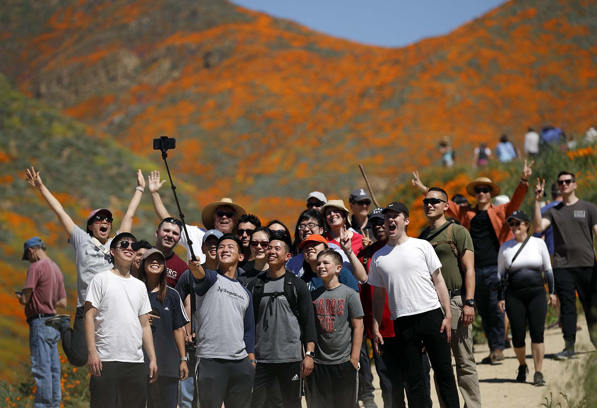 La gente posa para una foto entre flores silvestres en flor el lunes 18 de marzo de 2019, en Lake Elsinore, California, donde las amapolas naranjas iluminan las laderas (Foto: AP / Gregory Bull)