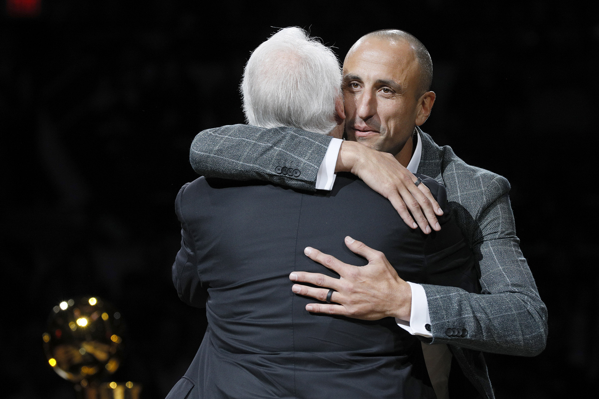 El ex jugador de los San Antonio Spurs, Manu Ginóbili (frente a la cámara), abraza al entrenador de los Spurs, Gregg Popovich, durante una ceremonia de retiro de su camiseta en el AT&T Center después de un partido entre los Cleveland Cavaliers y San Antonio Spurs