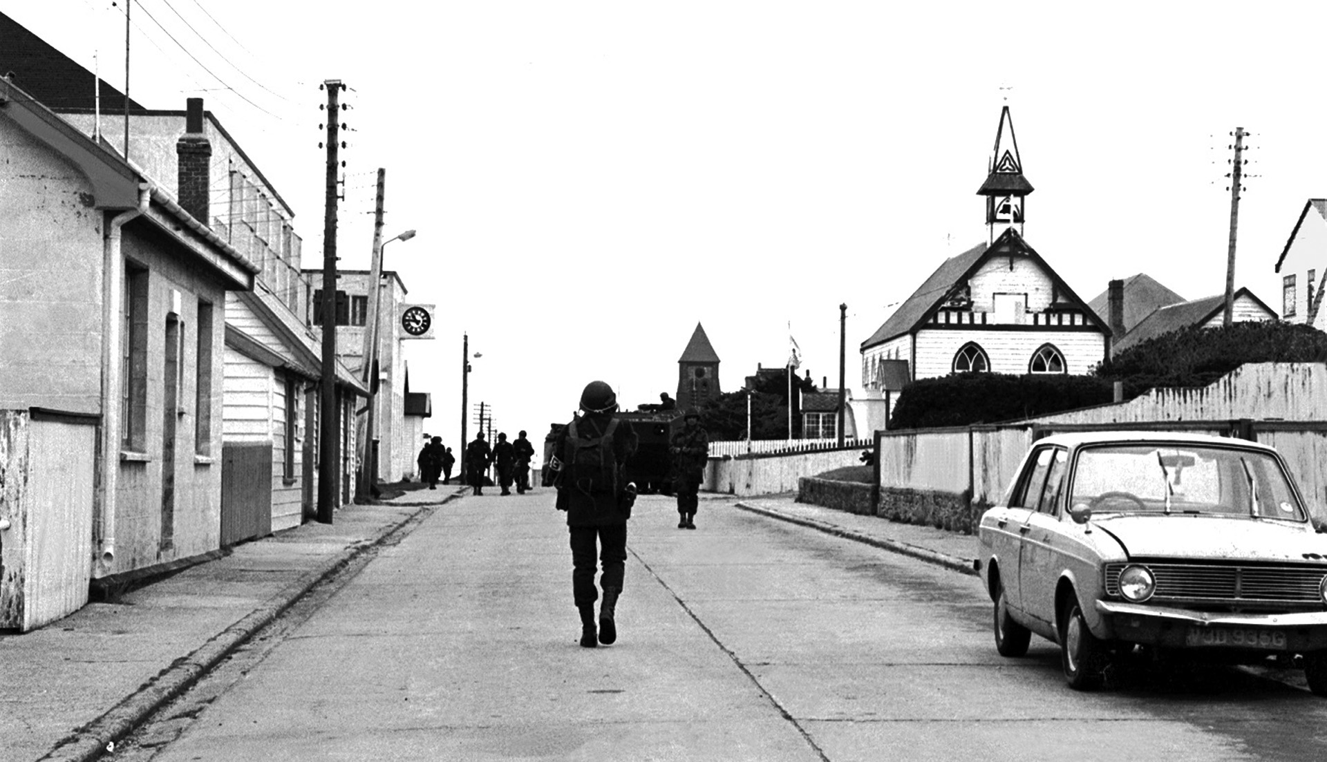 Las 10.46  de aquel 2 de abril. El soldado encabeza una de las tantas patrullas. Atrás, la iglesia católica de Saint Mary. Adelante, un auto inglés con el volante a la derecha, estacionado sobre la izquierda para circular en esa dirección. Al fondo, un vehículo anfibio argentino parece cumplir con las reglas de tránsito de las islas (Foto: Osvaldo Zurlo).