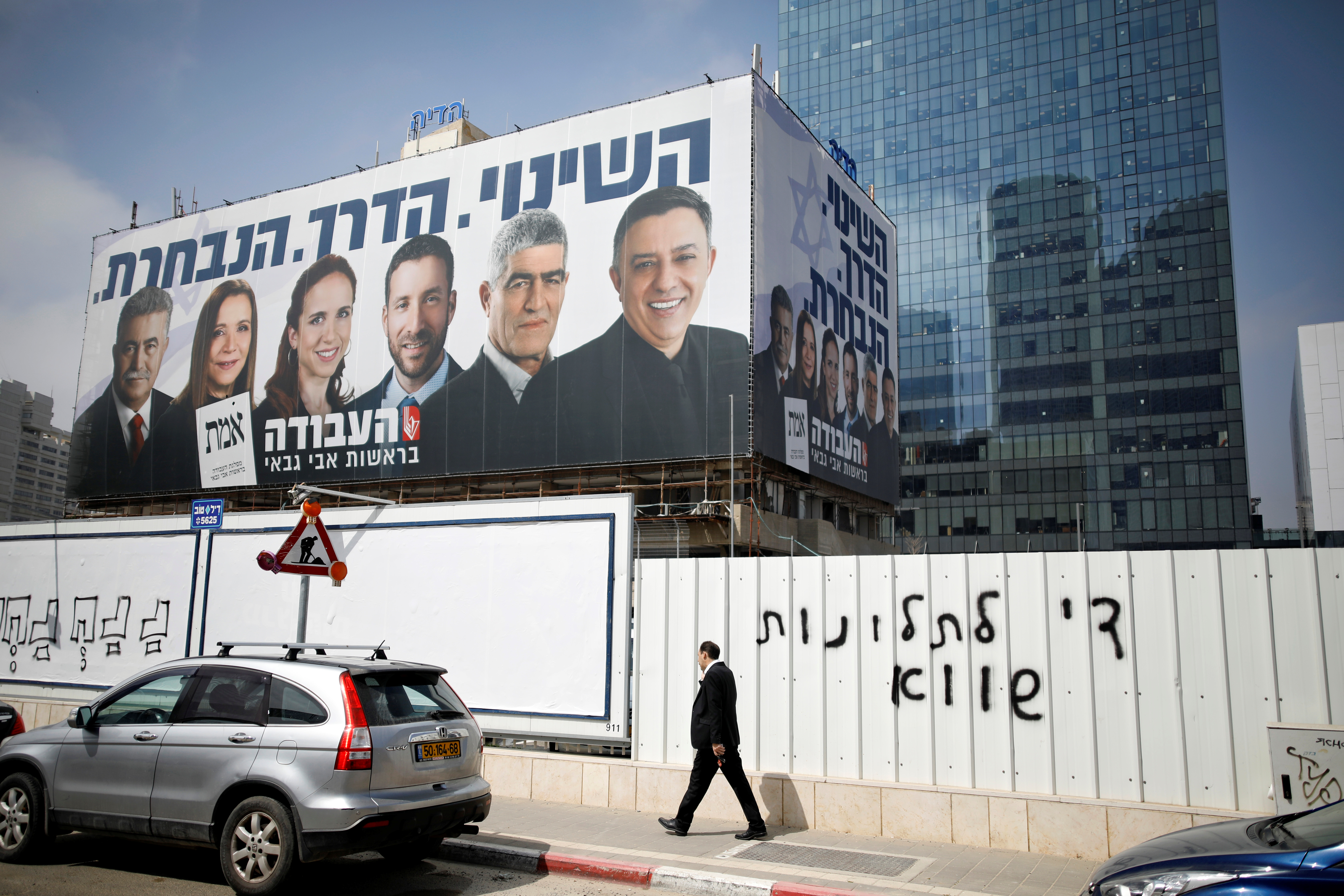 Un hombre camina frente a un propaganda del partido Laborista en Tel Aviv (REUTERS/Amir Cohen)