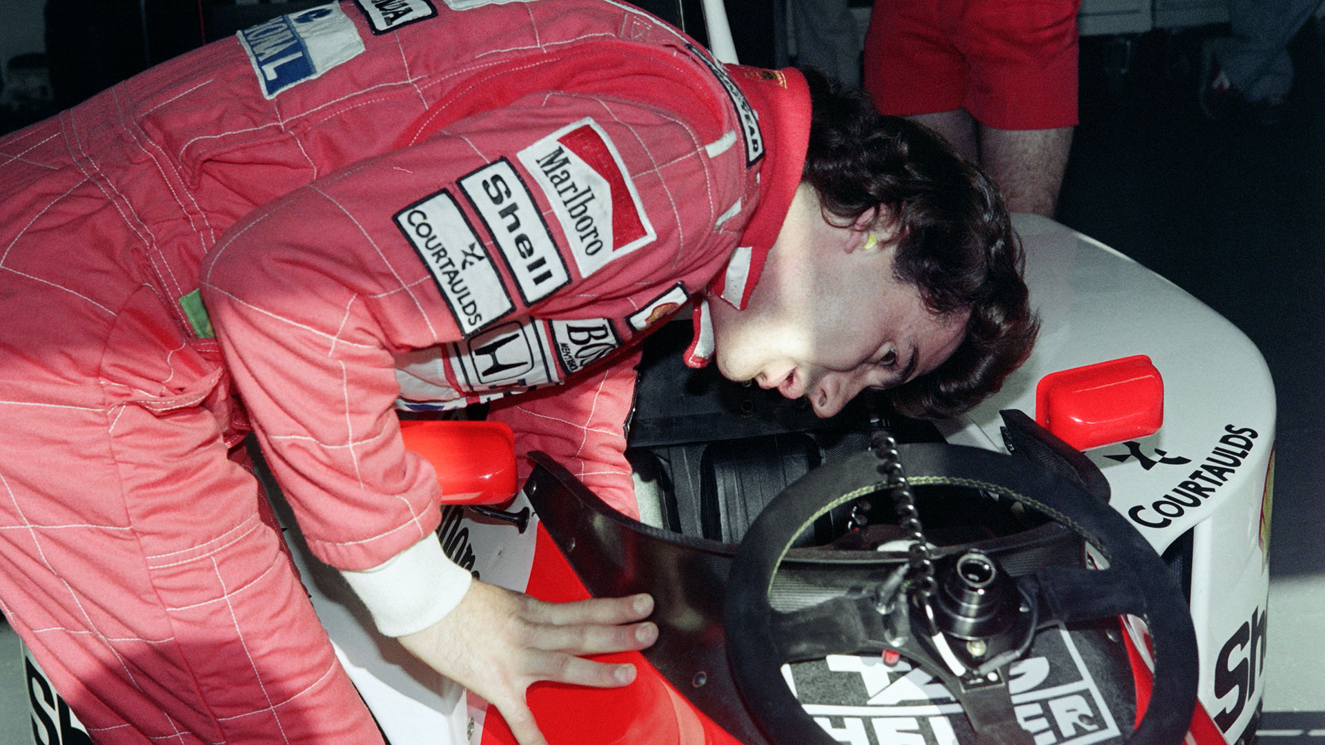 Senna mirando el interior del cockpit de su McLaren Honda durante una sesión de clasificación en el Gran Premio de Estororil, Portugal