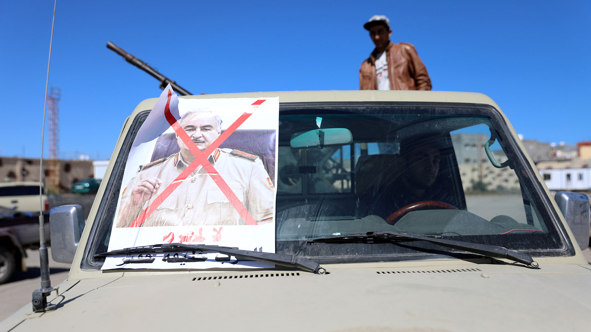 Un vehículo militar de miembros de milicias leales al gobierno en Trípoli, con una foto tachada de Haftar (Reuters)