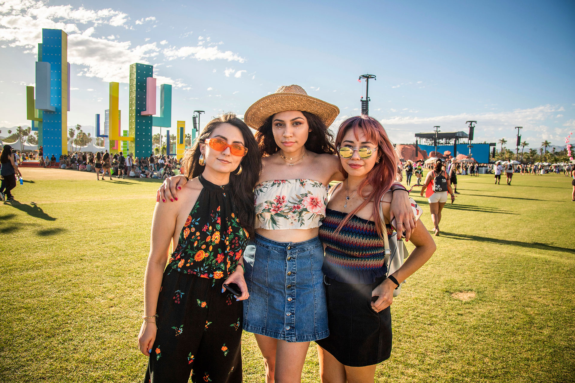 Tres estilos diferentes. Flower power con una monoprenda de cuello halter, un conjunto de dos piezas de top floreado con falda de tiro alto abotonada de denim y un estilo hippie chic con bandó plisado rainbow con falda de denim negro. Sus accesorios, anteojos de colores y sombrero Panamá