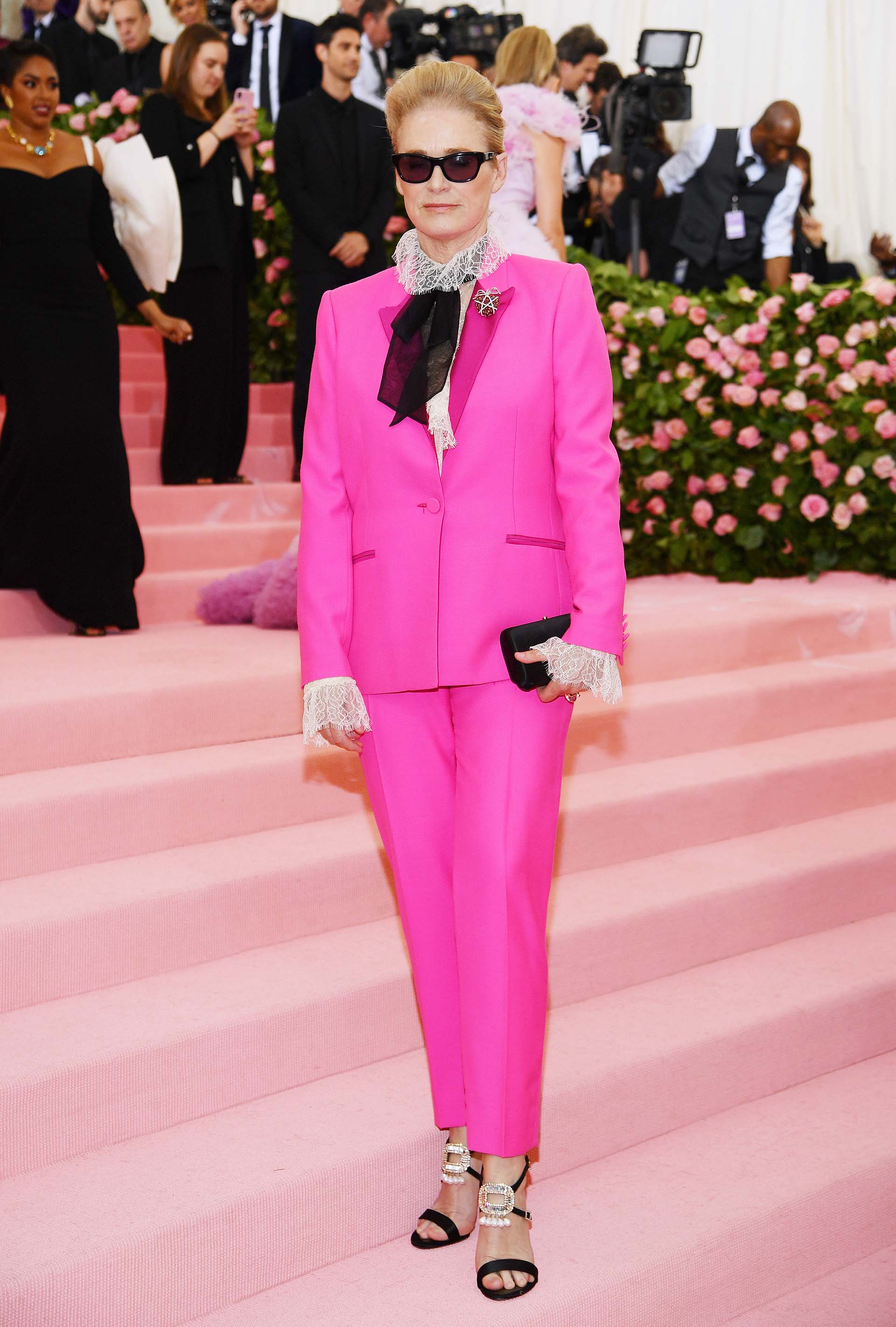 La directora de Vogue West Coast y Teen Vogue Lisa Love lució un traje de sastre fucsia con una camisa de estilo antiguo y mangas con volados, y sandalias negras de verano con detalles de perlas. Por supuesto, con gafas de sol oscuras