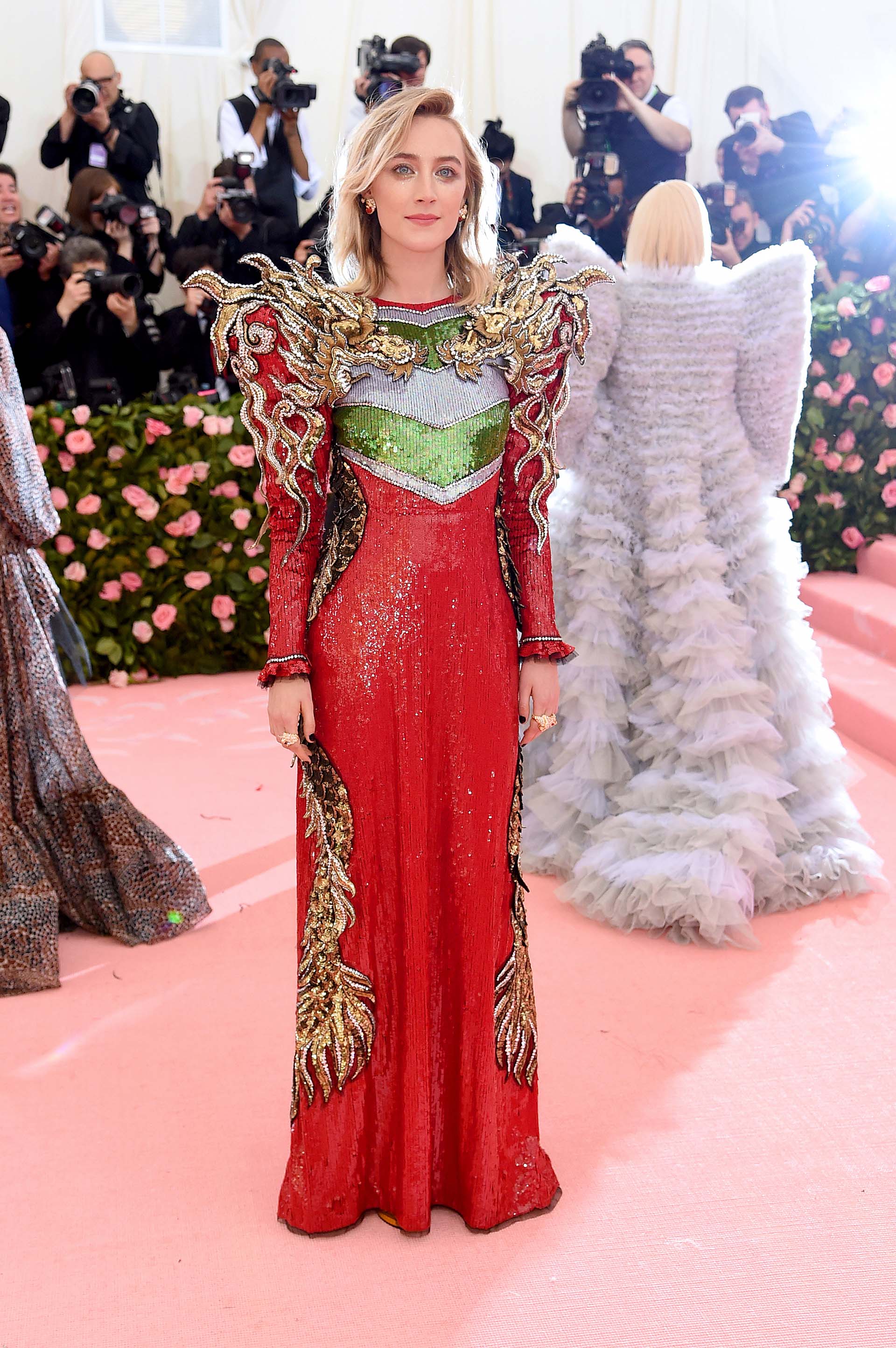 Saoirse Ronan en un “power suit” rojo, verde y dorado de hombreras y flamas de fuego