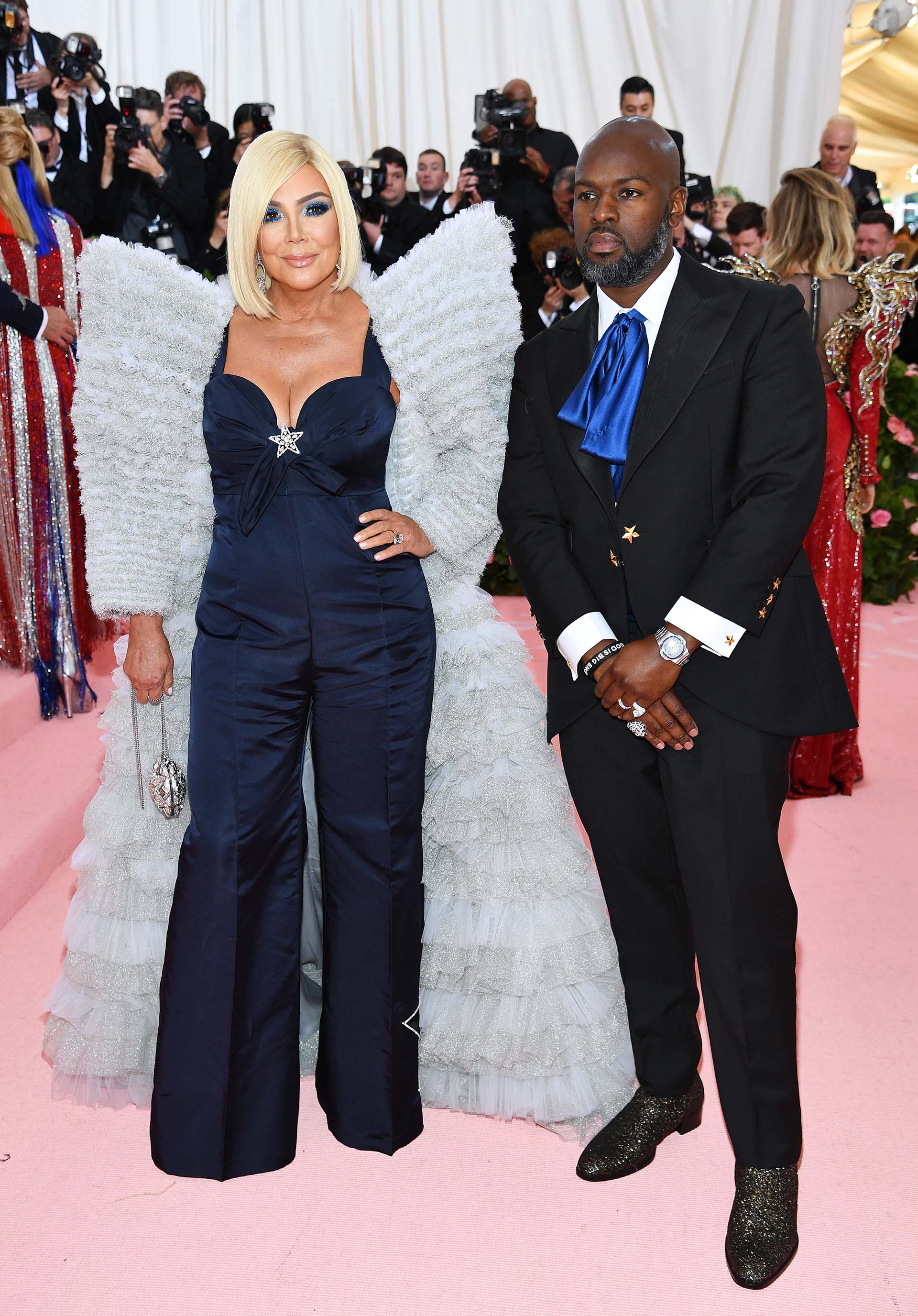 Kris Jenner acompañada por su pareja Corey Gamble, esta vez con el cabello rubio, optó por un traje azul noche y una capa color pastel