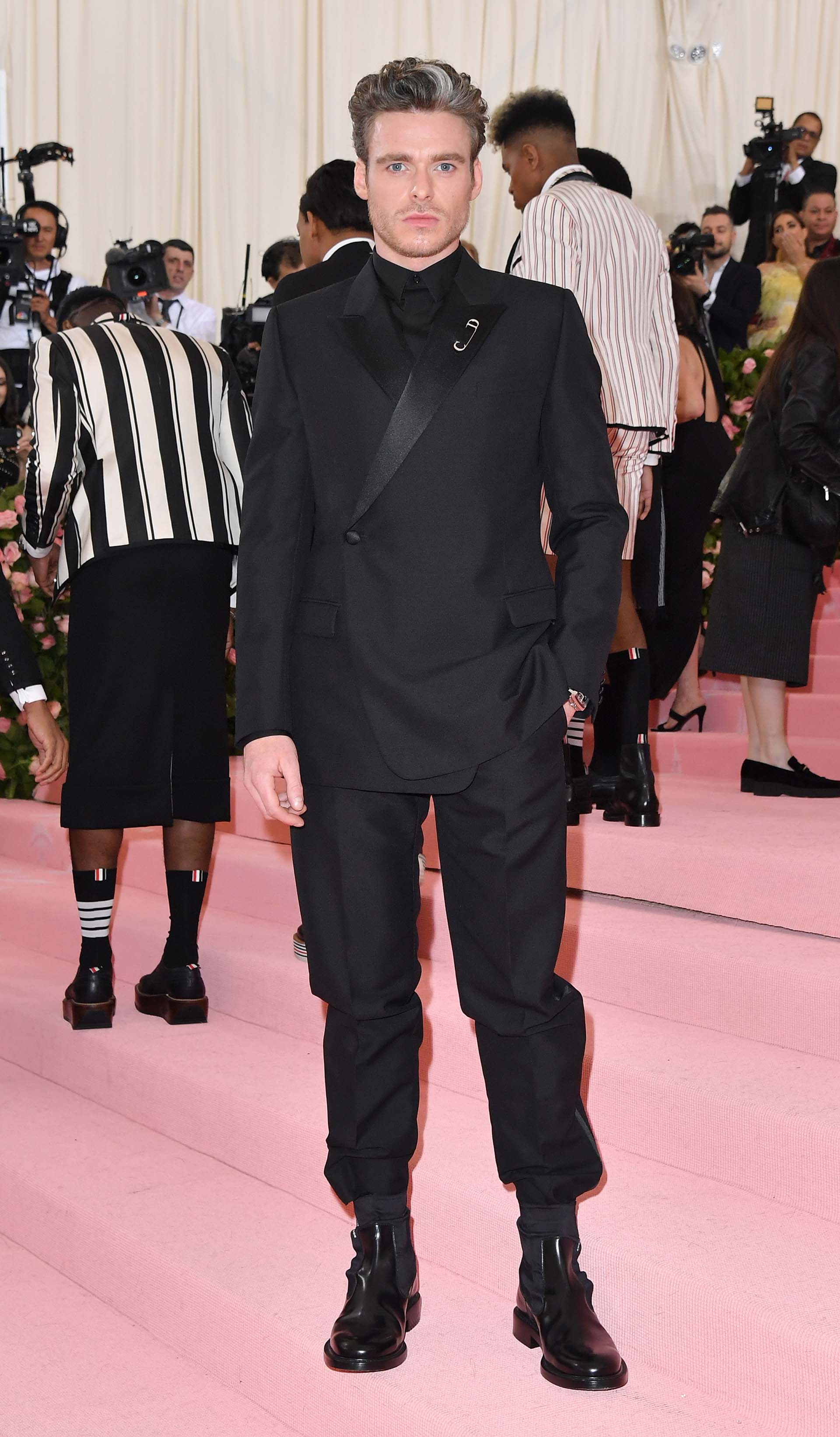 El actor escocés Richard Madden lució un elegante esmoquin negro, botas, camisa y broche de Dior Men