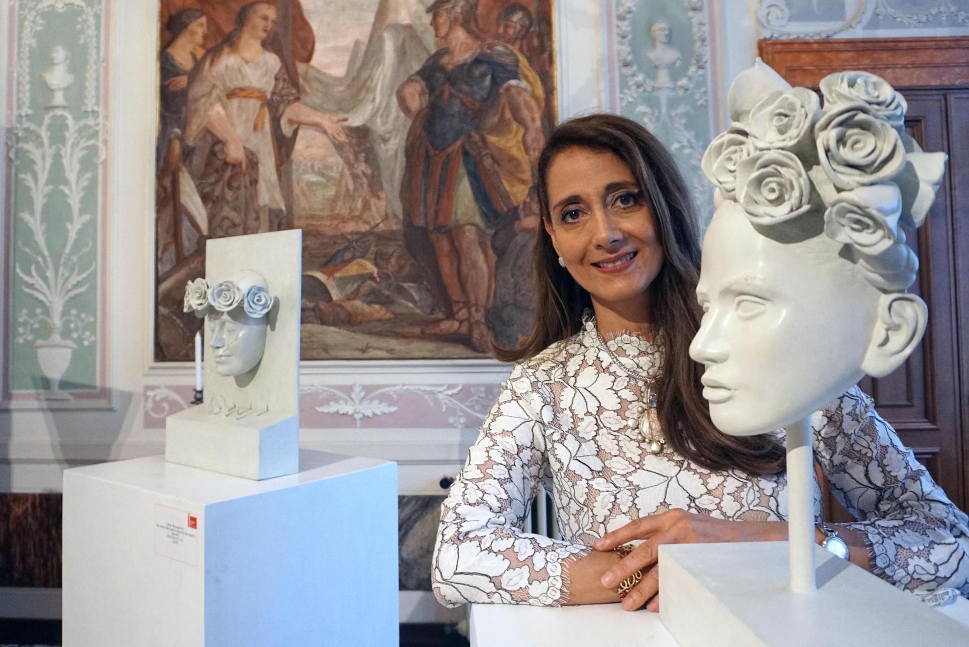 Elsie Wunderlich posa junto a varias de sus obras que se exponen en el pabellón de Guatemala (EFE/ Andrea Merola)