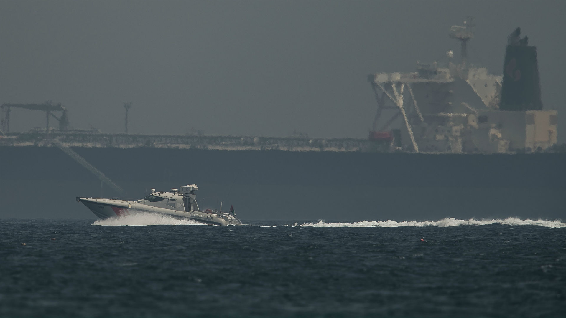 Un navío de la Guardia Costera emiratí pasa junto a un petrolero frente a la costa de Fujairah, Emiratos Árabes Unidos, el lunes 13 de mayo de 2019. (AP Foto/Jon Gambrell)