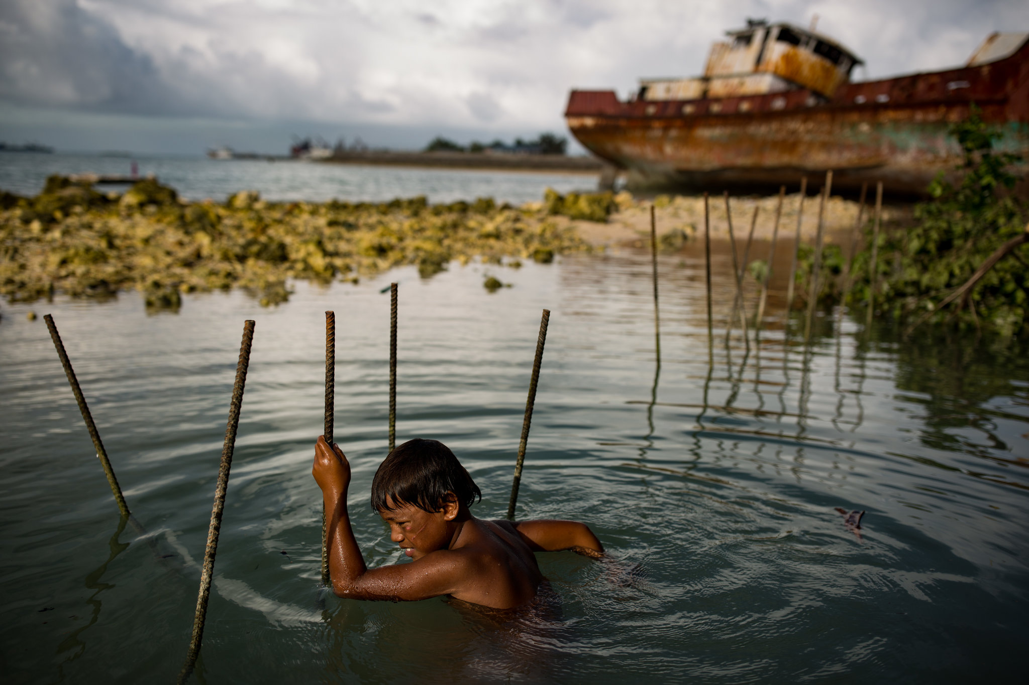 En Betio, Tarawa Sur, Toobeen Iareko, de 6 años, jugaba con varillas que son usadas para construir un nuevo muro marino frente a otra barrera que falló permitiendo la llegada del agua durante la Marea del Rey. Febrero de 2015. (Josh Haner/The New York Time)